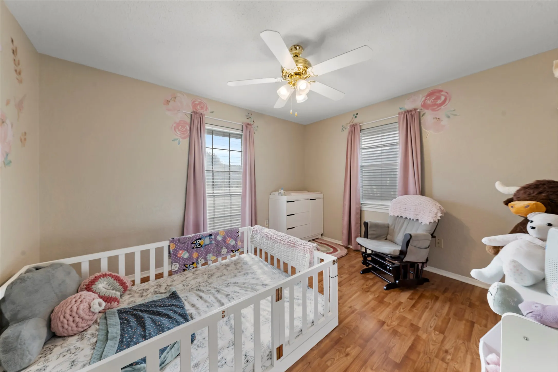 Bedroom featuring light wood finished floors, a ceiling fan, and a nursery area