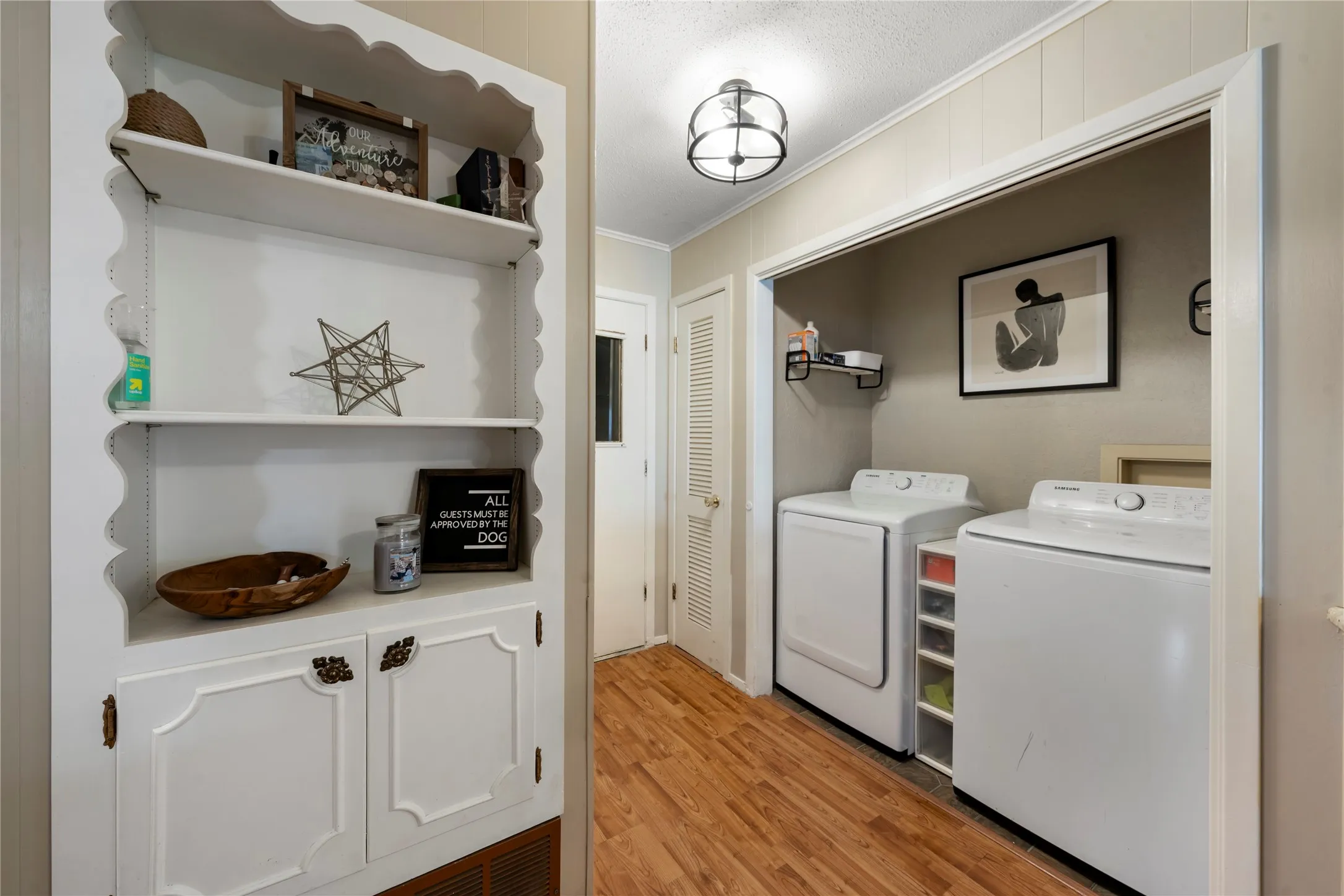 Laundry room featuring ornamental molding, light wood-style floors, washing machine and clothes dryer, and a textured ceiling