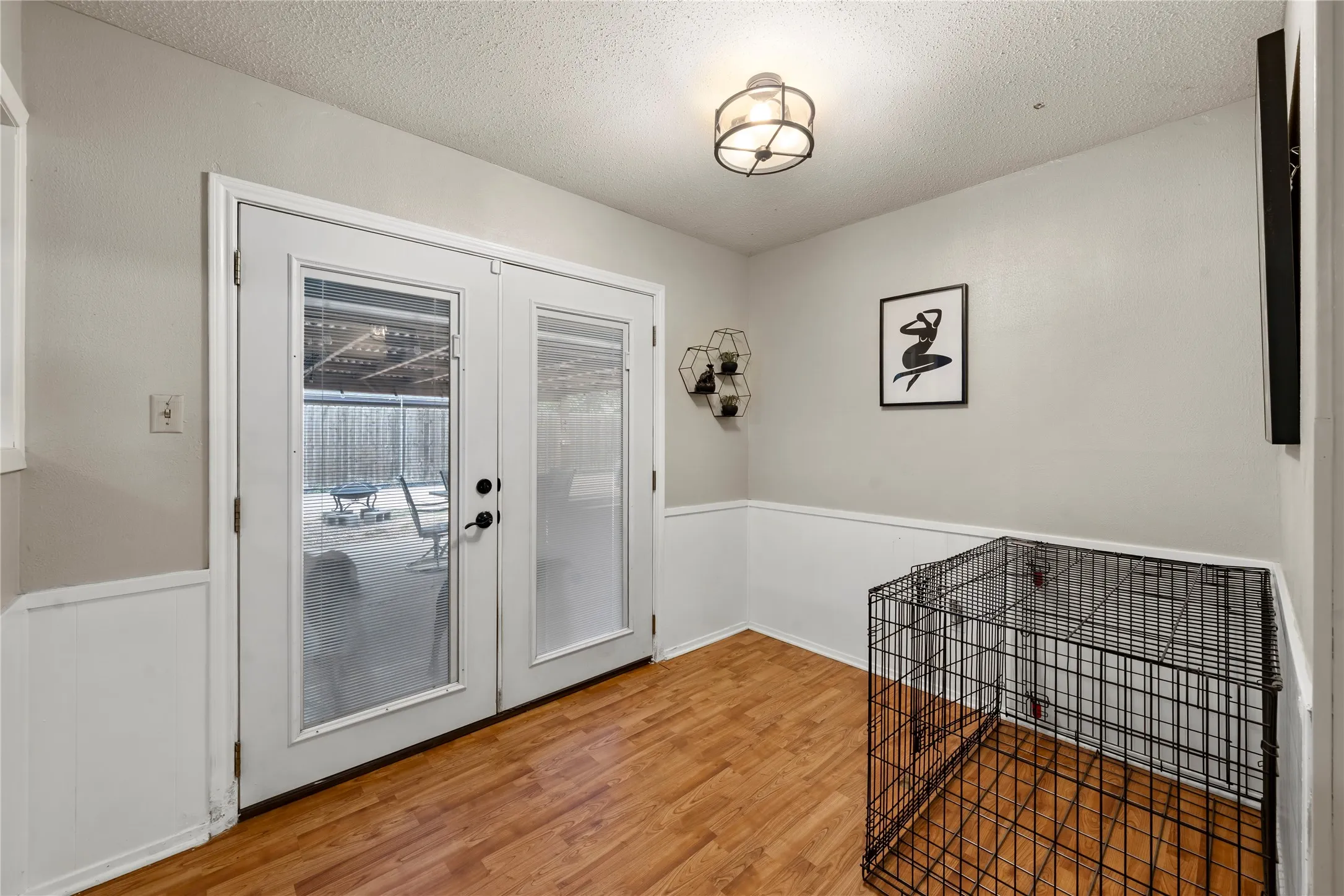 Entryway featuring wood finished floors, a textured ceiling, and wainscoting
