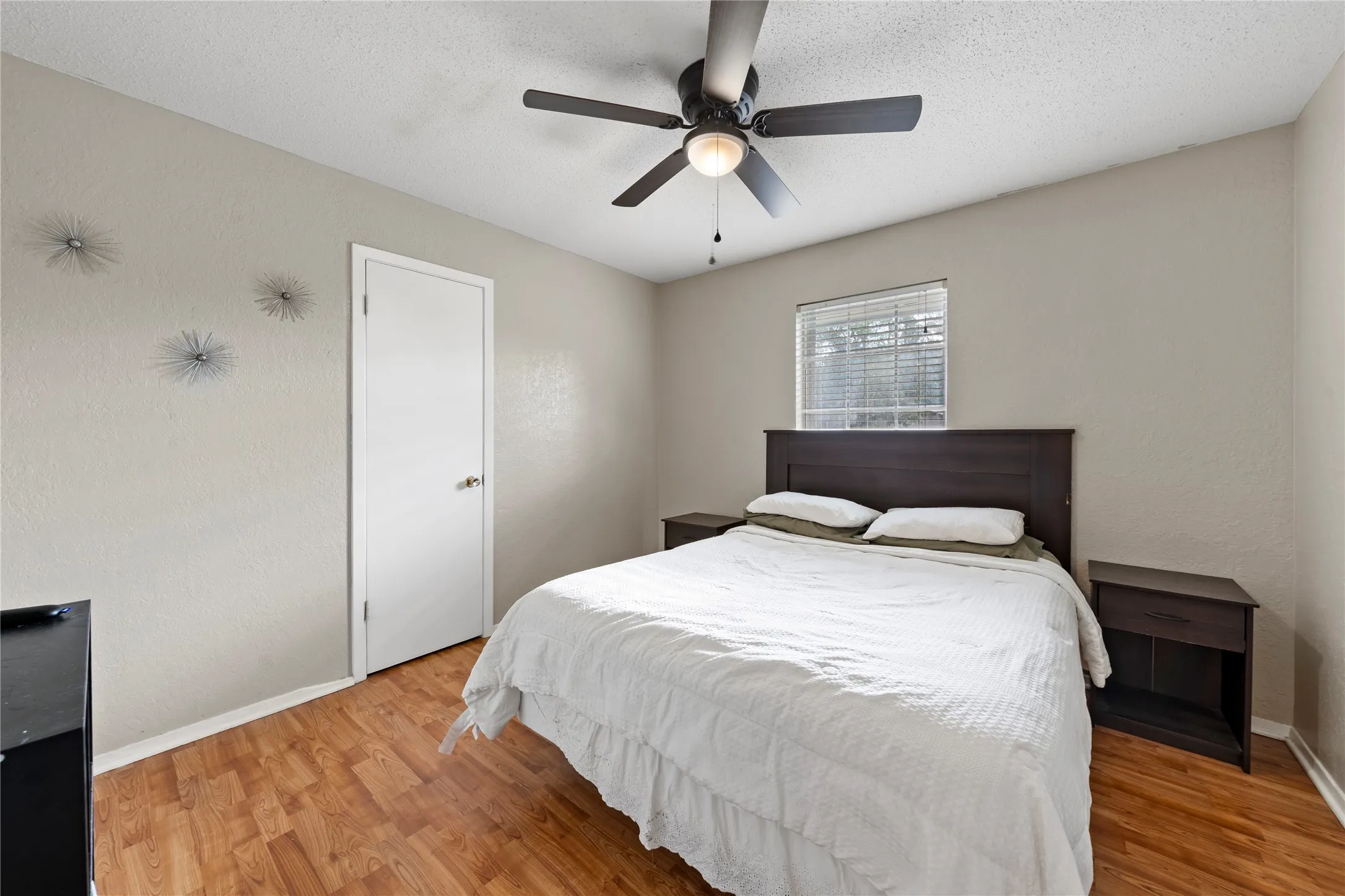 Bedroom with light wood-type flooring, a ceiling fan, a textured ceiling, and a textured wall