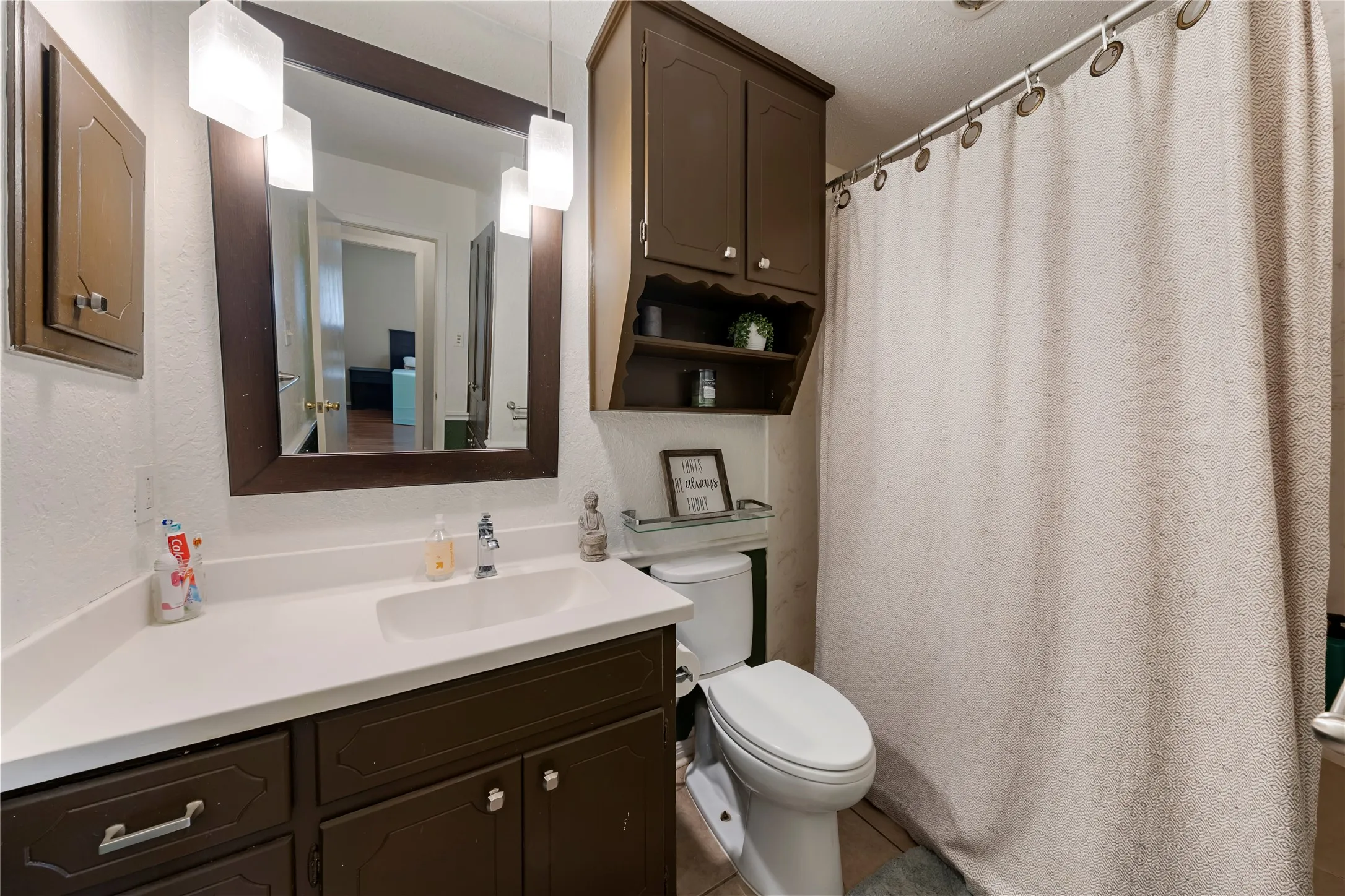Bathroom with vanity, curtained shower, and a textured wall
