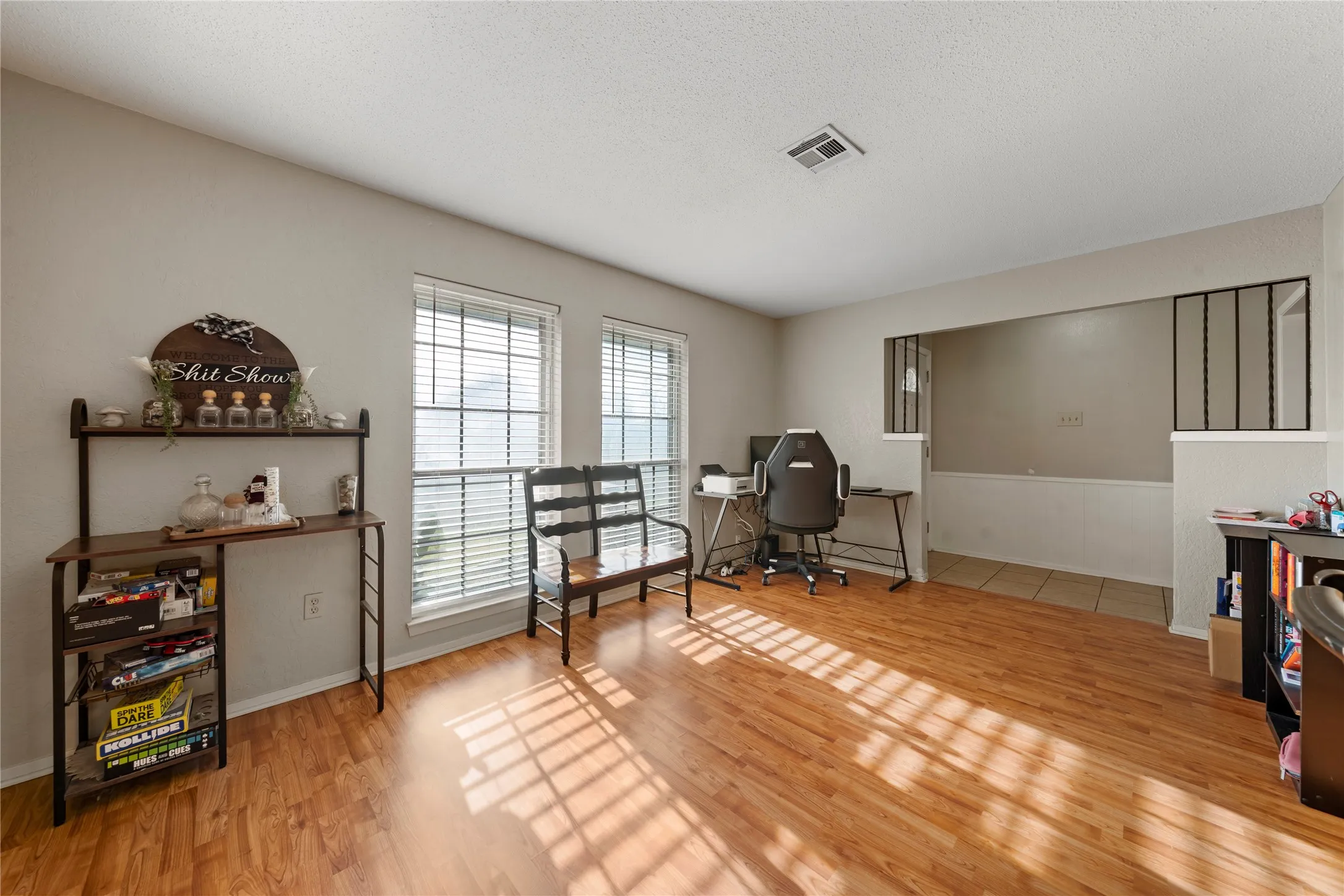 Home office with light wood-type flooring and a textured ceiling