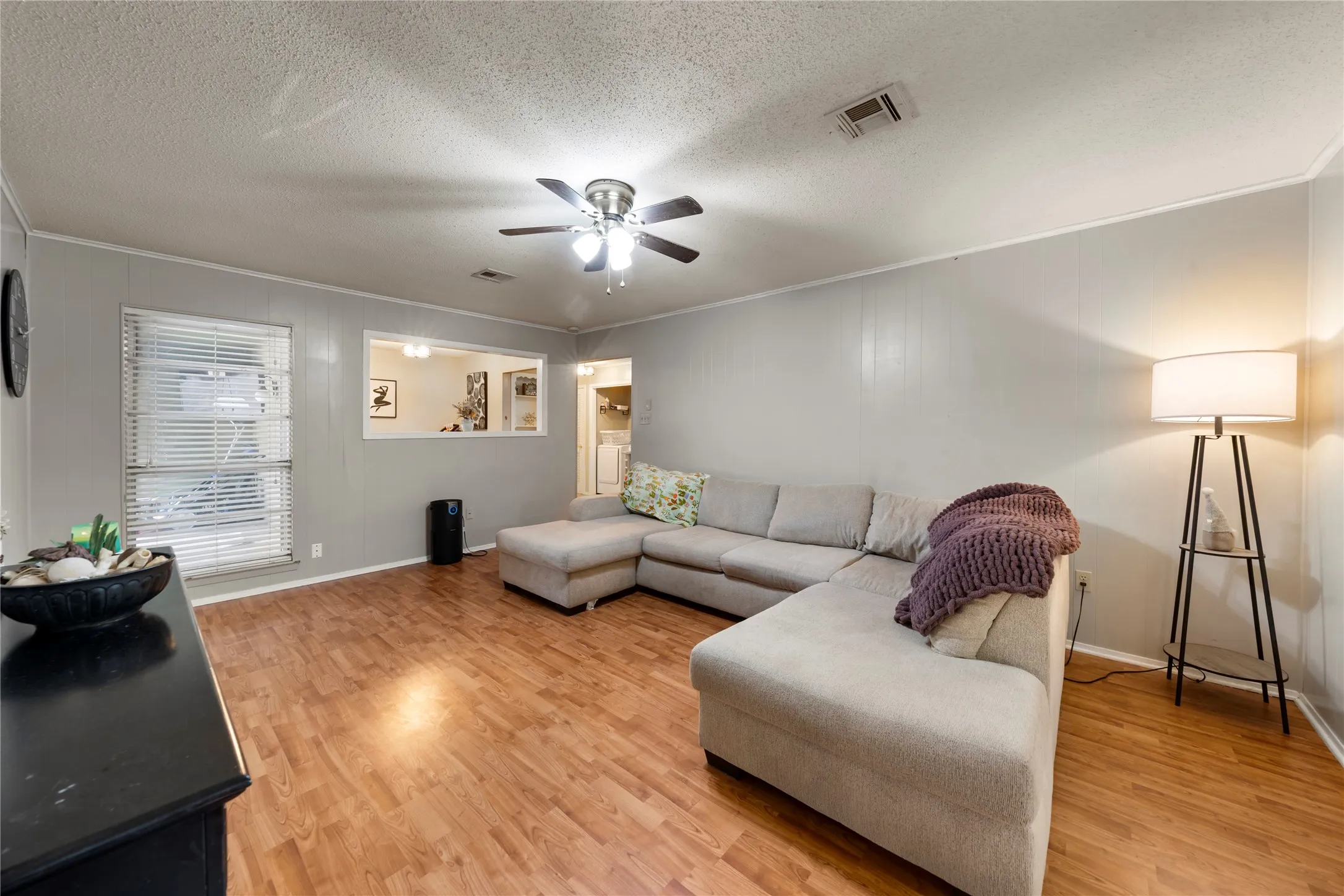 Living area with ornamental molding, light wood-style floors, a textured ceiling, and ceiling fan