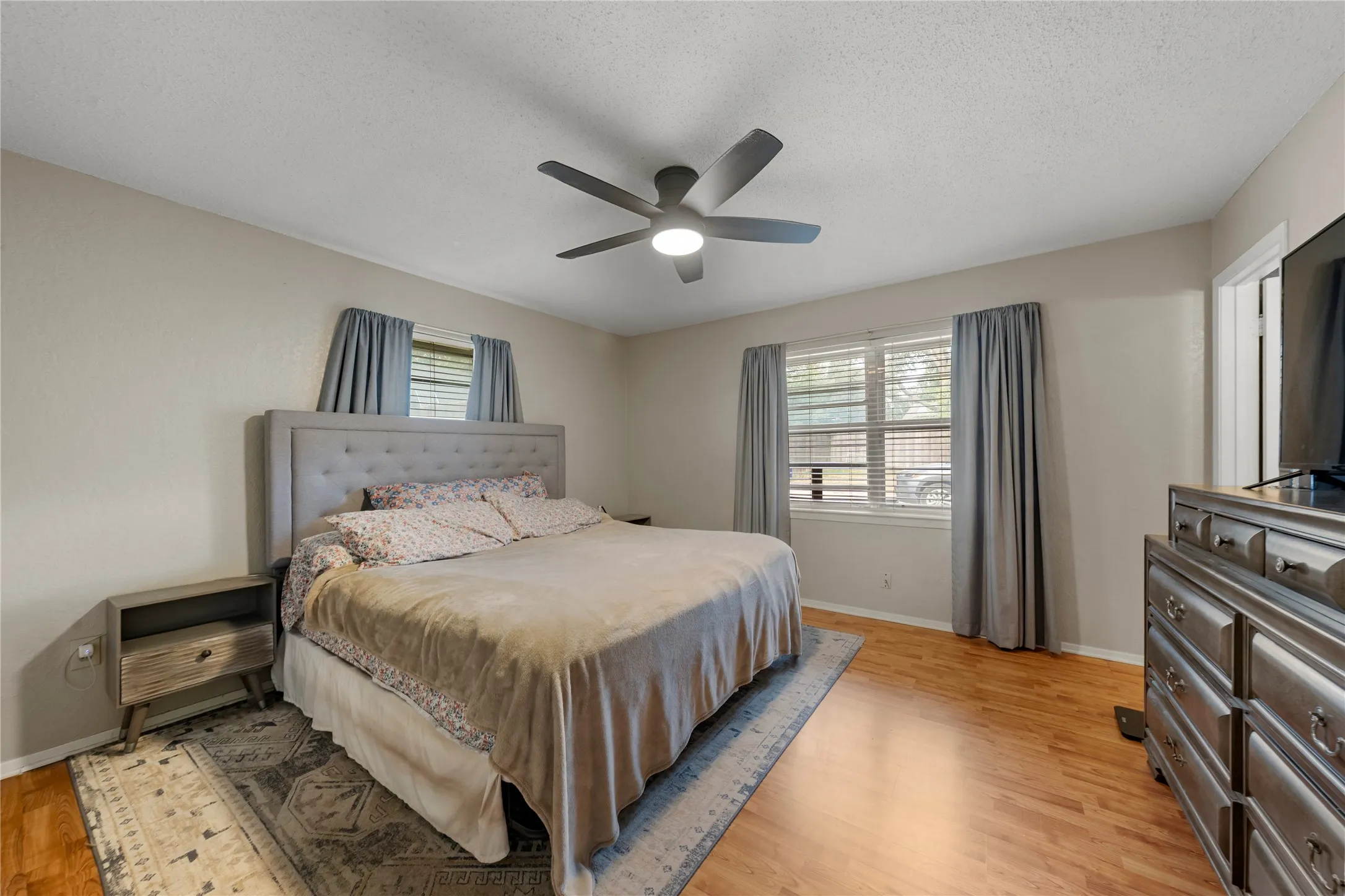 Bedroom featuring light wood finished floors, a ceiling fan, and a textured ceiling