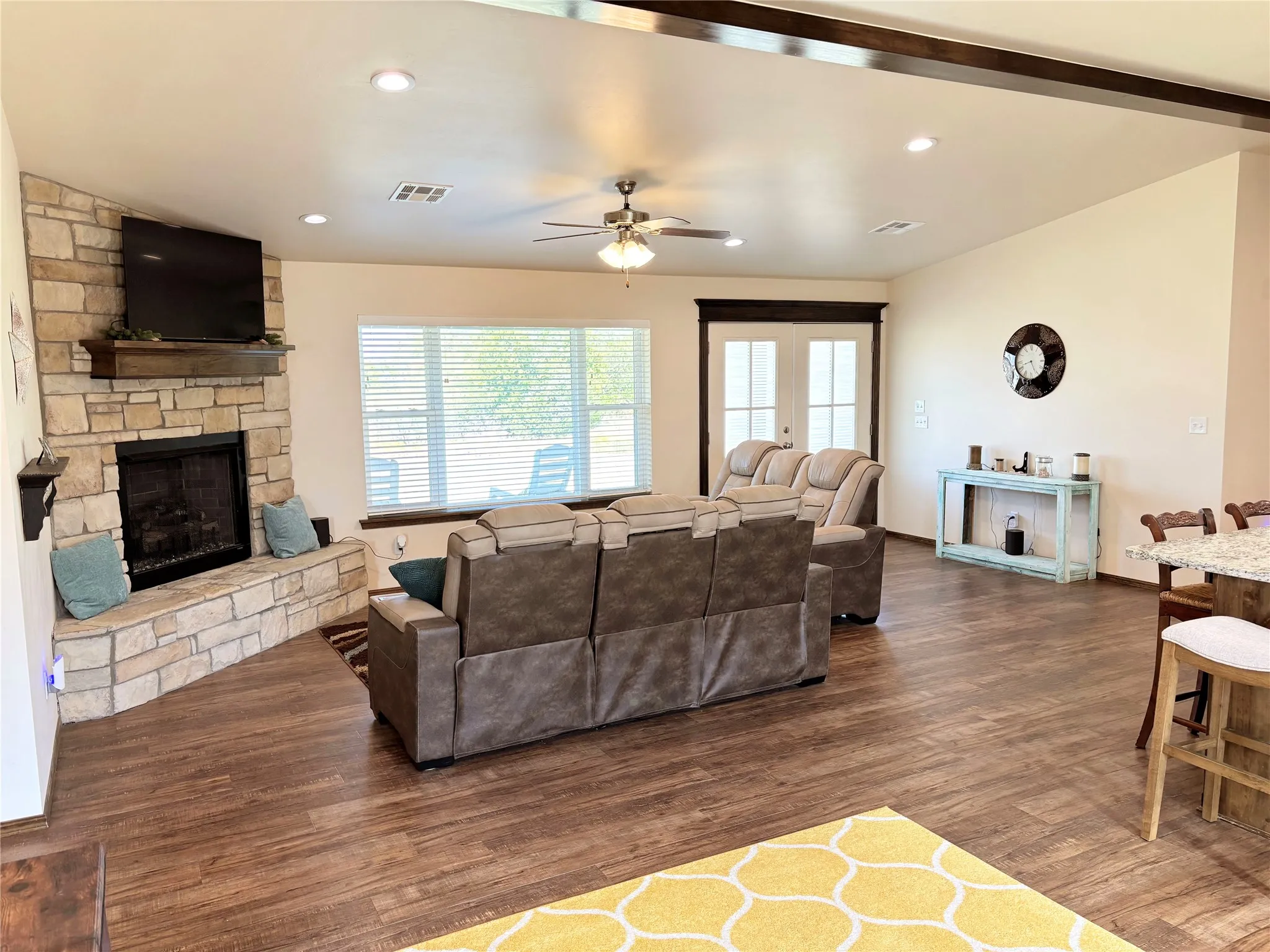 Living area featuring a stone fireplace, a ceiling fan, and recessed lighting
