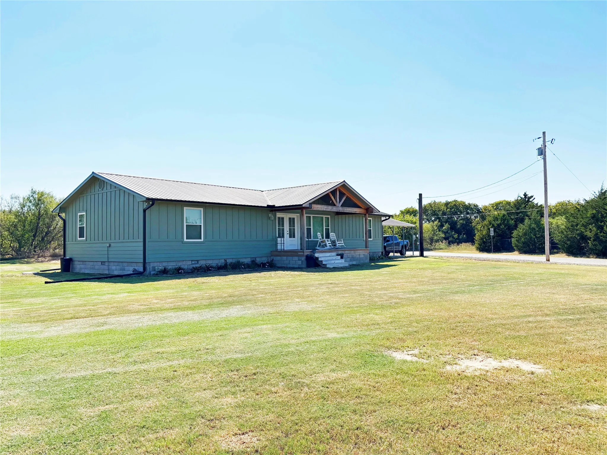 View of front of home featuring a porch, a front lawn, crawl space, and a metal roof