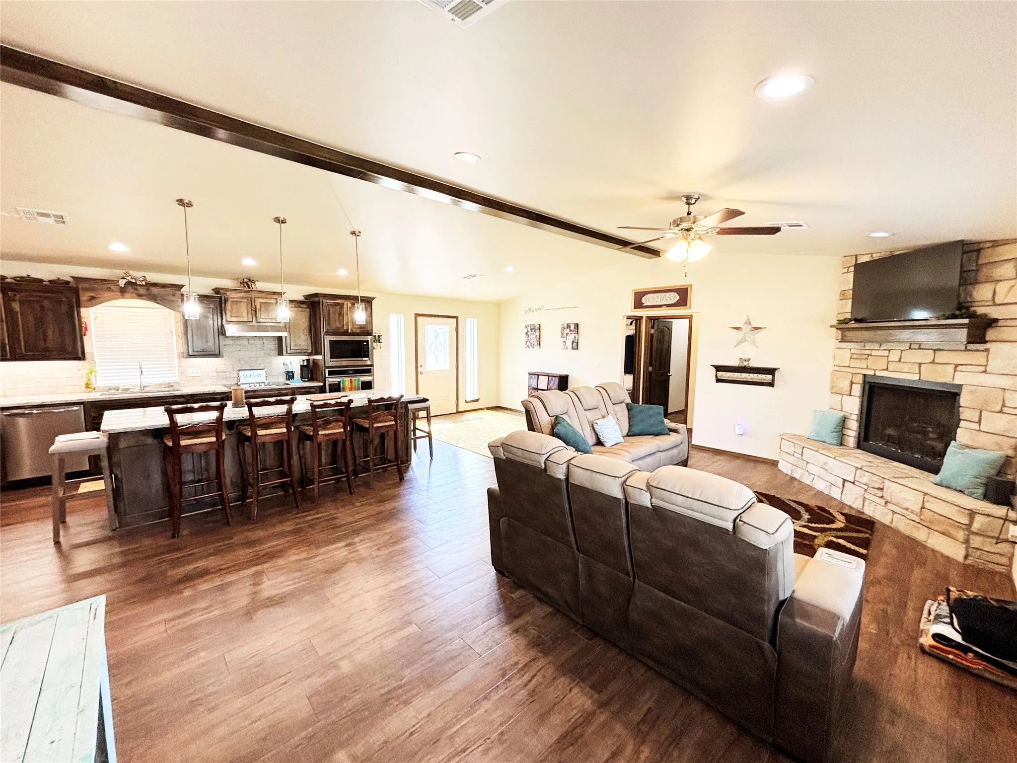 Living area with Luxury vinyl plank flooring, a ceiling fan, a stone fireplace, and recessed lighting