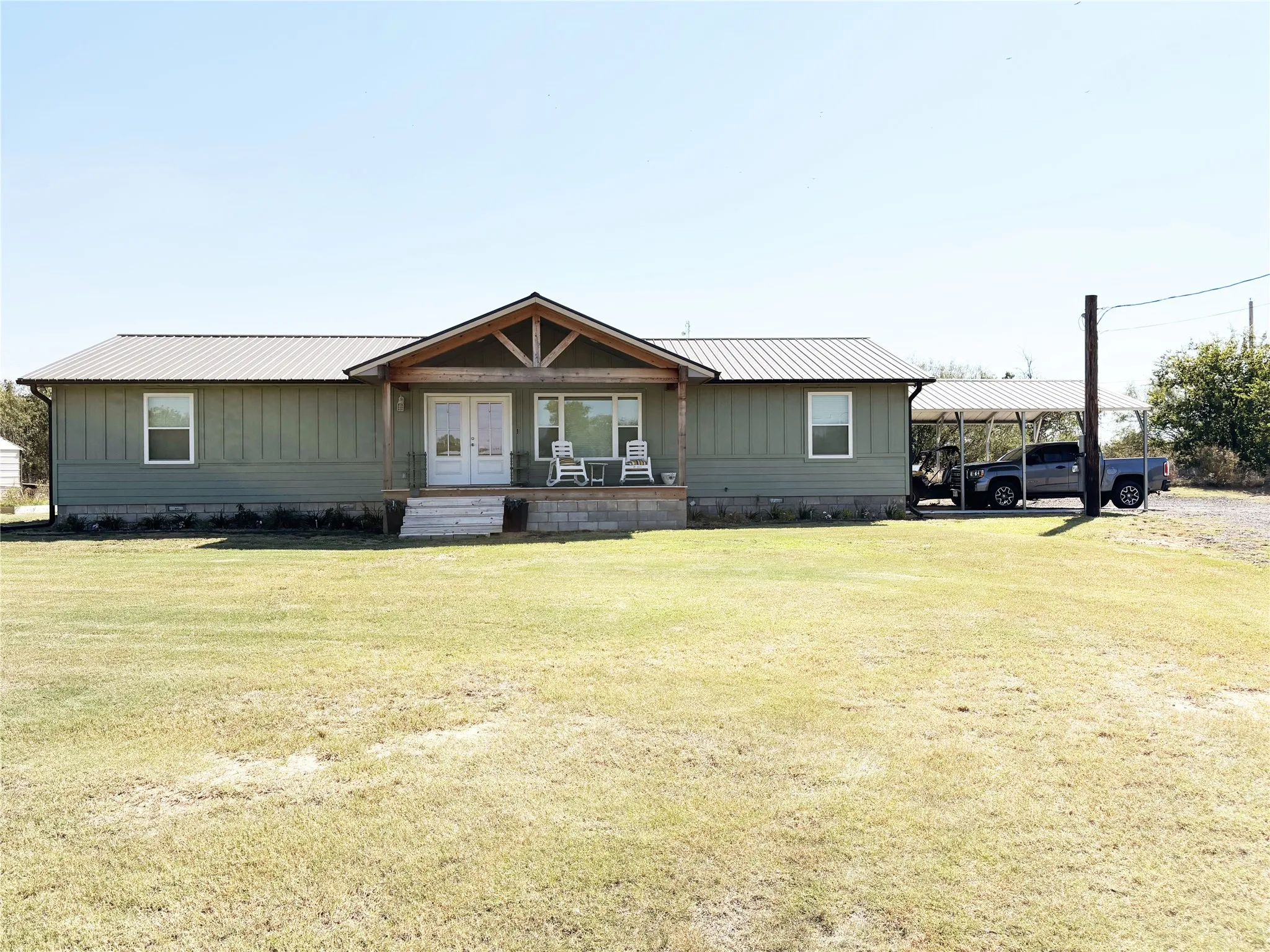 Front of house with a metal roof, a front lawn, and covered porch