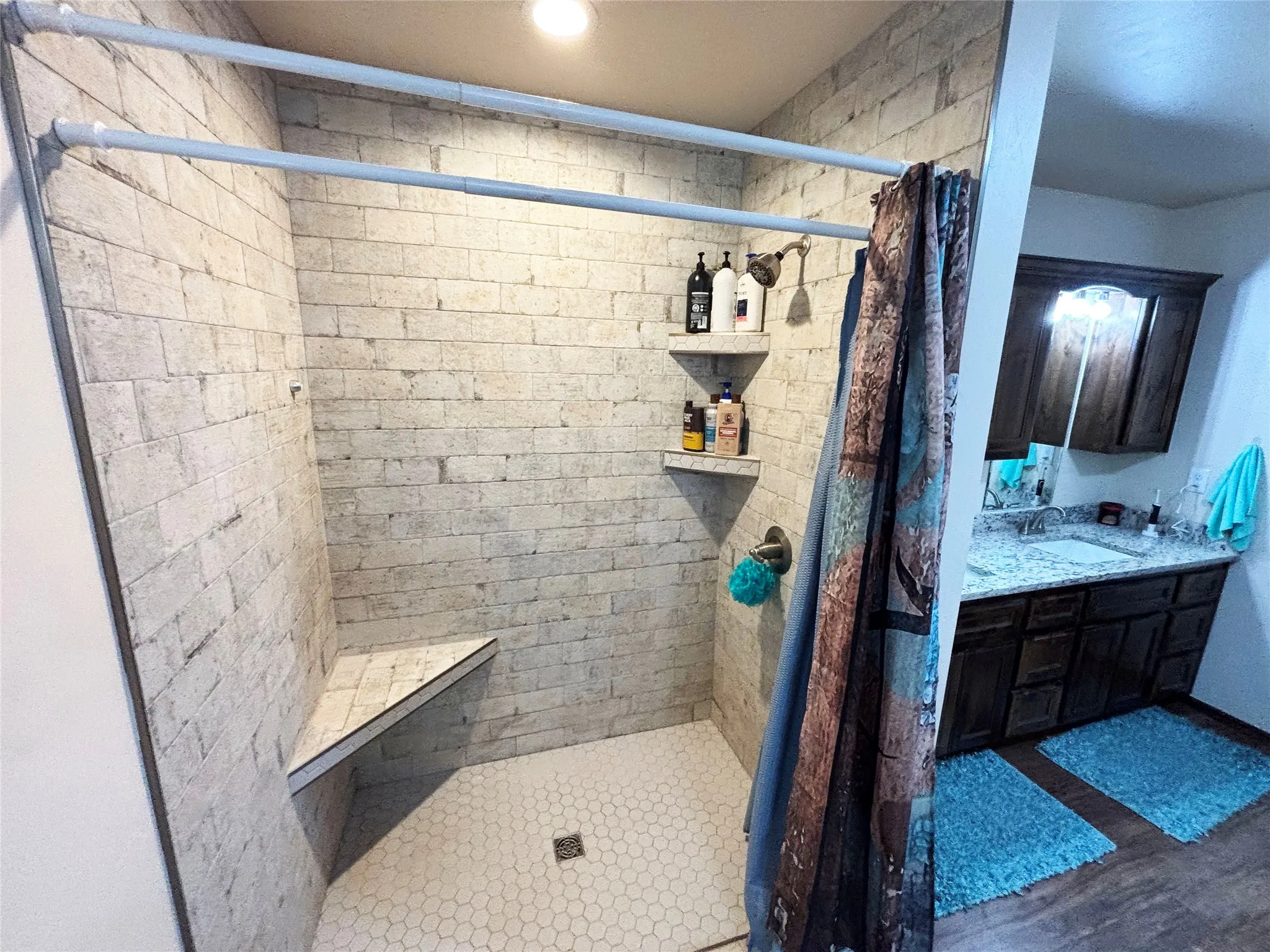 Full bath with a stall shower, vanity, and dark wood-style flooring