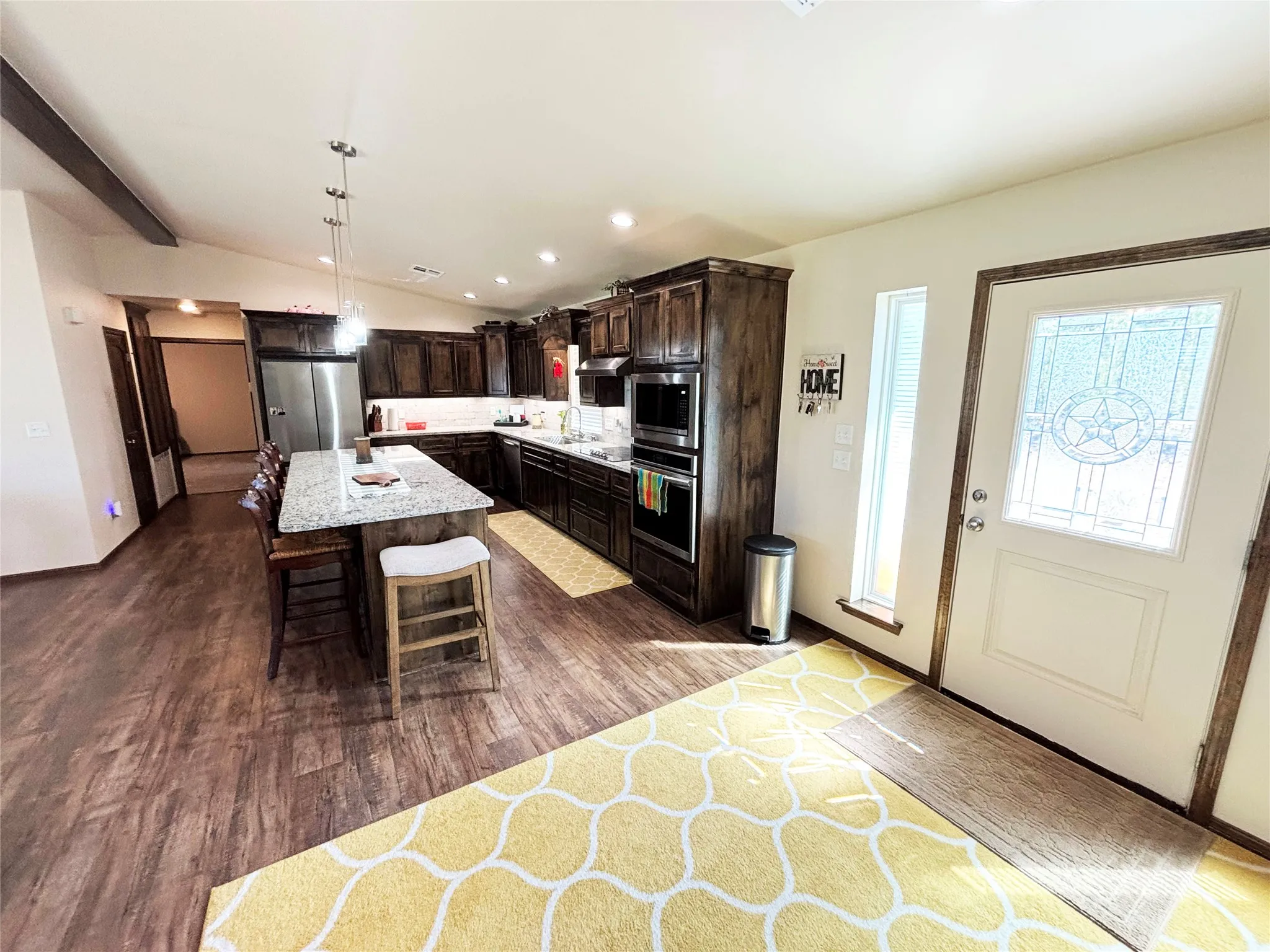 Kitchen featuring dark brown cabinetry, recessed lighting, dark wood-type flooring, a breakfast bar, and appliances with stainless steel finishes