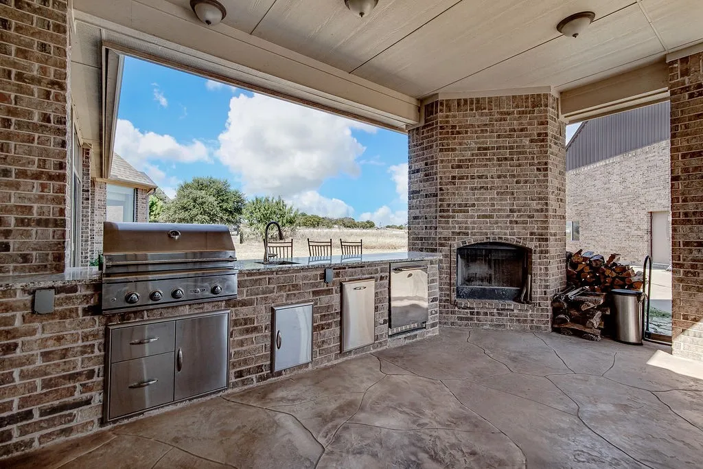 View of patio / terrace with exterior kitchen and an outdoor brick fireplace