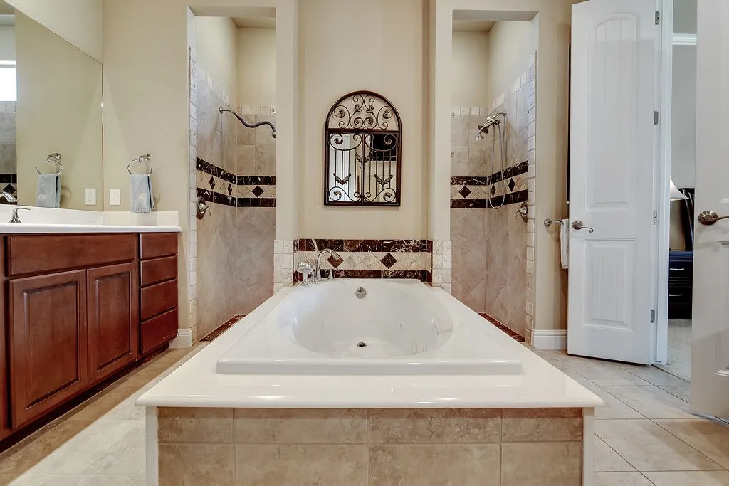 Full bathroom featuring a garden tub, light tile patterned floors, and vanity