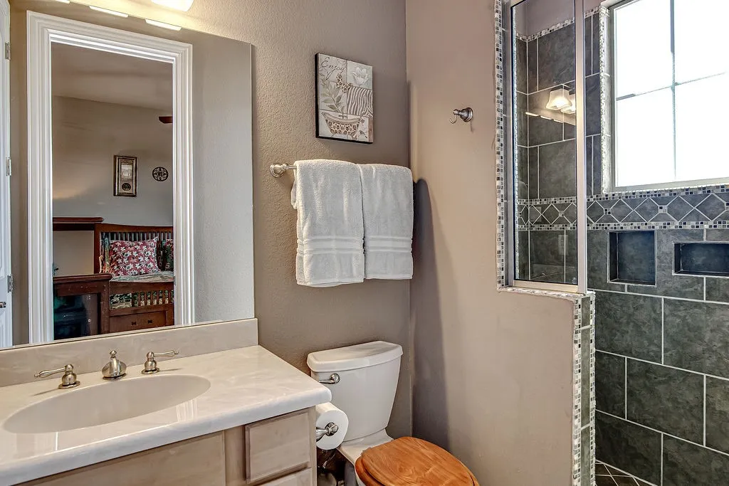 Bathroom featuring a textured wall, a walk in shower, and vanity