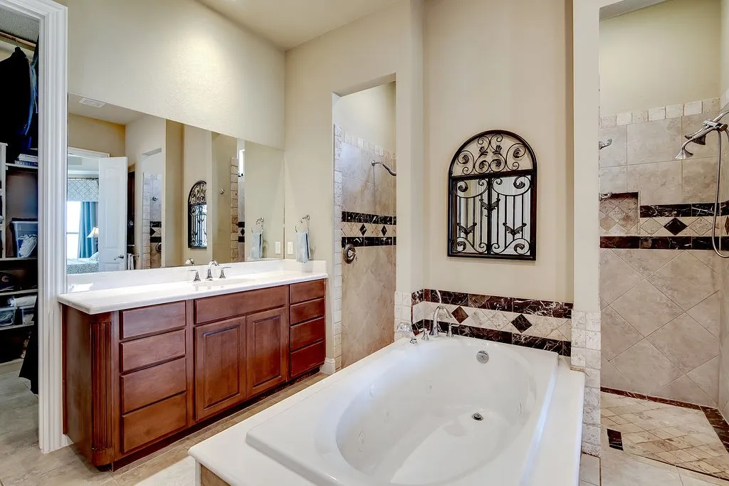 Full bathroom featuring a tub with jets, vanity, light tile patterned floors, and a walk in shower
