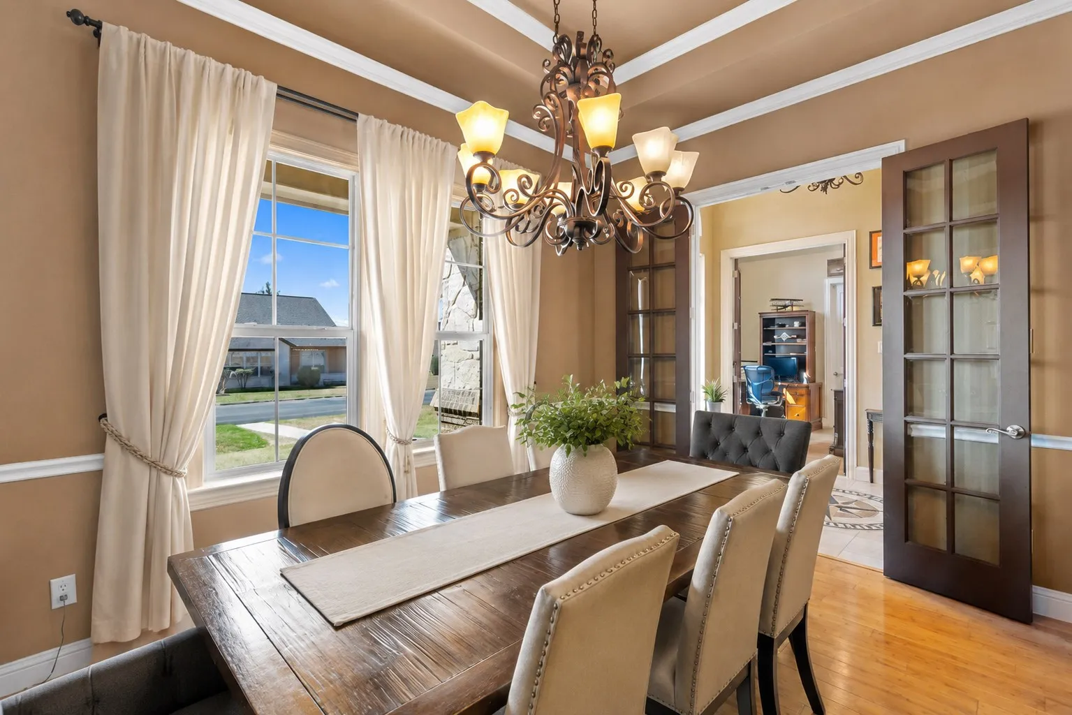 Tray ceiling with decorative trim, wood-finish flooring, two large windows, elegant chandelier, and double French doors with glass panes