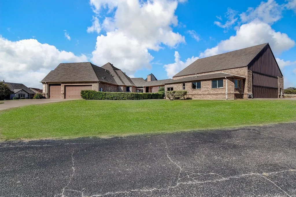 View of front of home featuring a front yard, an attached garage, driveway, and brick siding