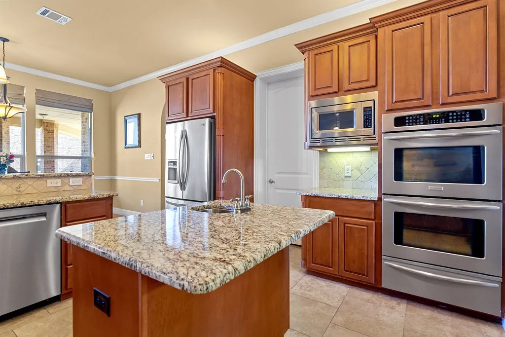 Kitchen featuring tasteful backsplash, stainless steel appliances, ornamental molding, and light stone countertops