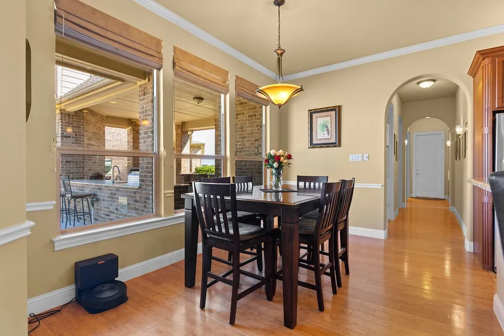 Dining area featuring arched walkways, light wood-style floors, and crown molding