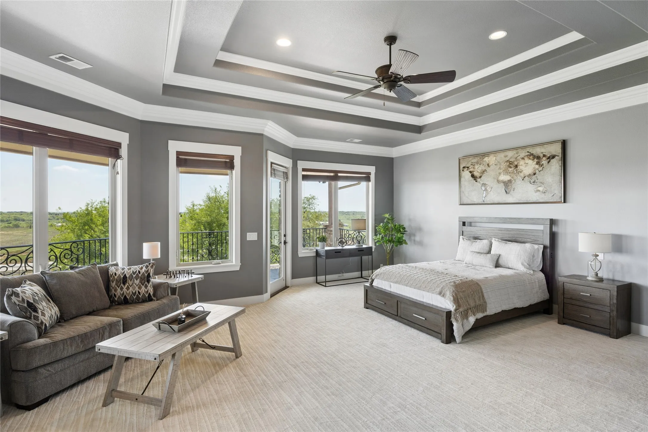 Spacious room featuring multiple windows with outdoor access, a tray ceiling with recessed lighting and a ceiling fan, and light-toned carpet flooring