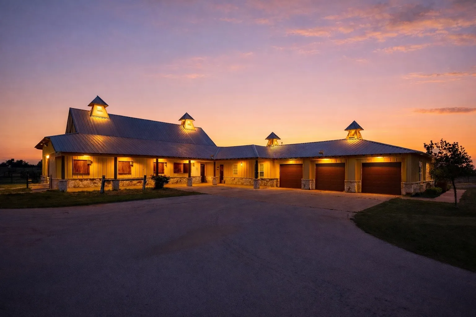 Spacious exterior featuring a metal roof, dormer vents, multiple garage bays, stone accents, and a large paved driveway