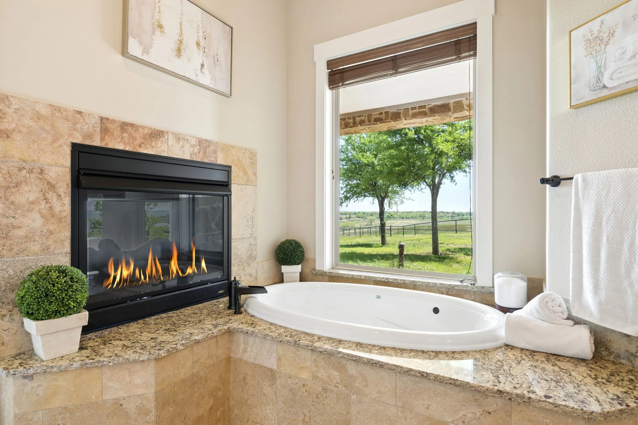 Luxurious soaking tub with surrounding granite countertop and travertine tile accents