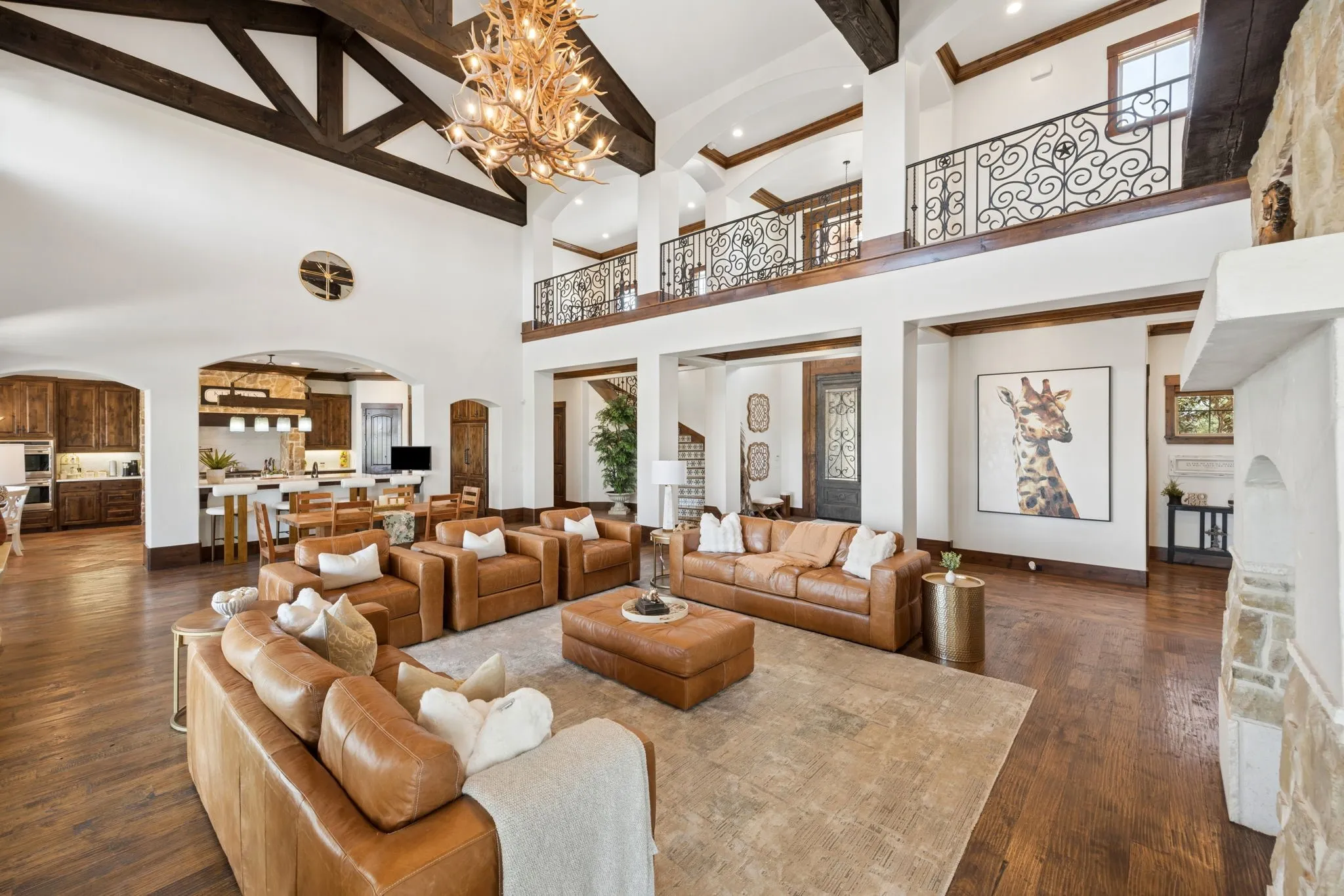 Great room featuring a vaulted ceiling with exposed wood beams, a two-story stone fireplace, and dark wood-finish flooring
