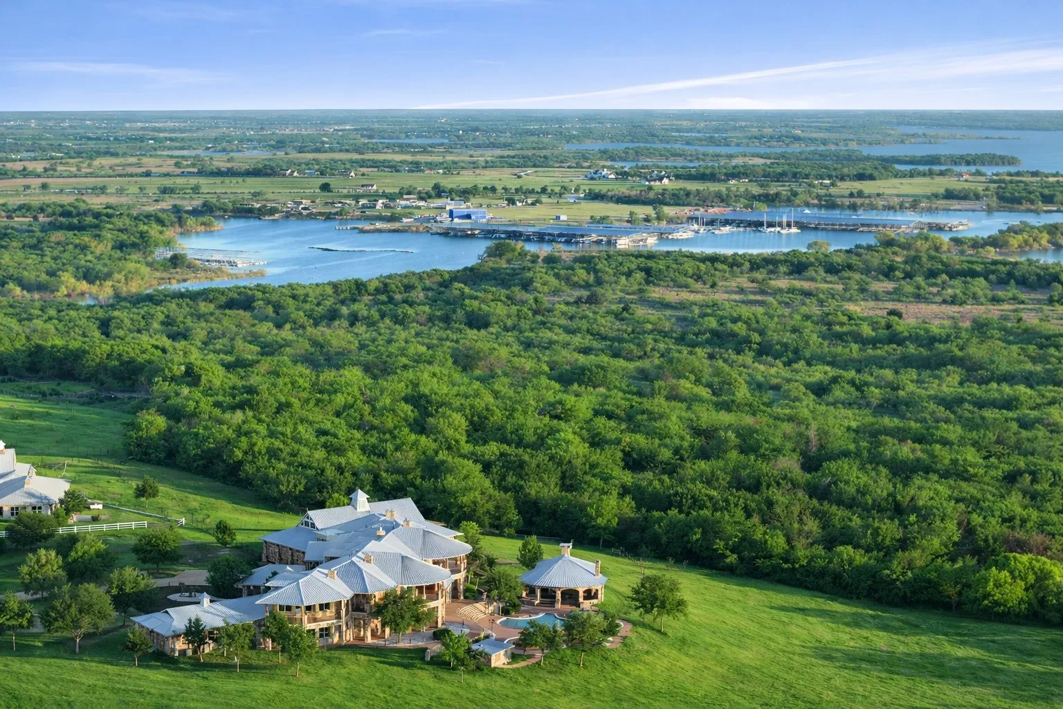 Expansive estate featuring multiple structures, a manicured lawn, and mature trees