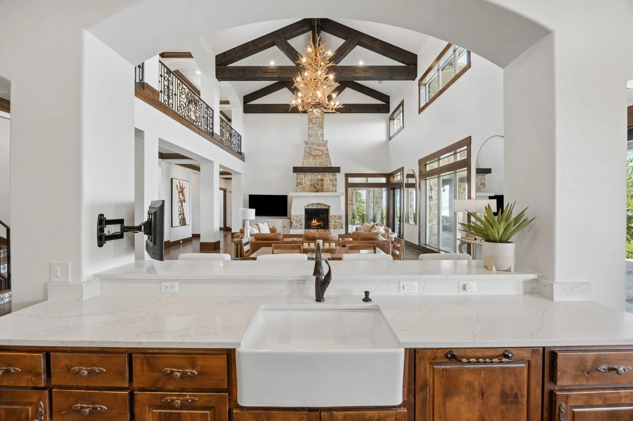 Kitchen counter featuring a large farmhouse sink with a dark-finish faucet, light-toned countertops, and rich wood cabinetry