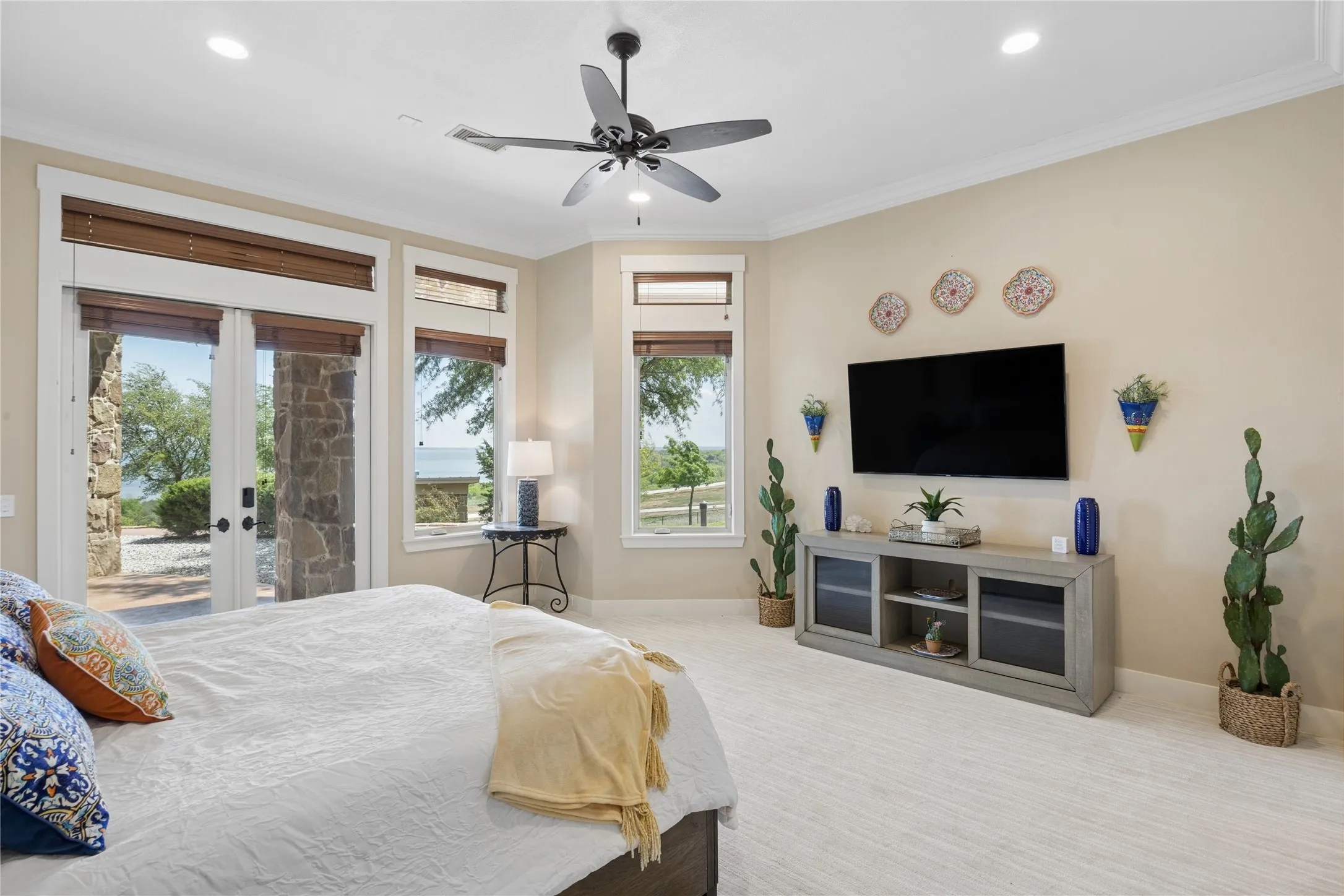 Expansive room featuring multiple windows and glass French doors, a ceiling fan with integrated lighting, recessed lighting, and crown molding