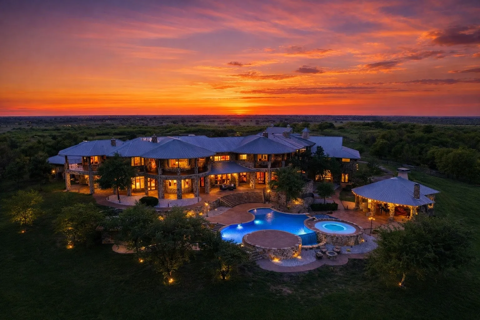 Expansive estate featuring multiple levels of covered outdoor living spaces, a freeform swimming pool, an integrated spa, and a separate covered pavilion