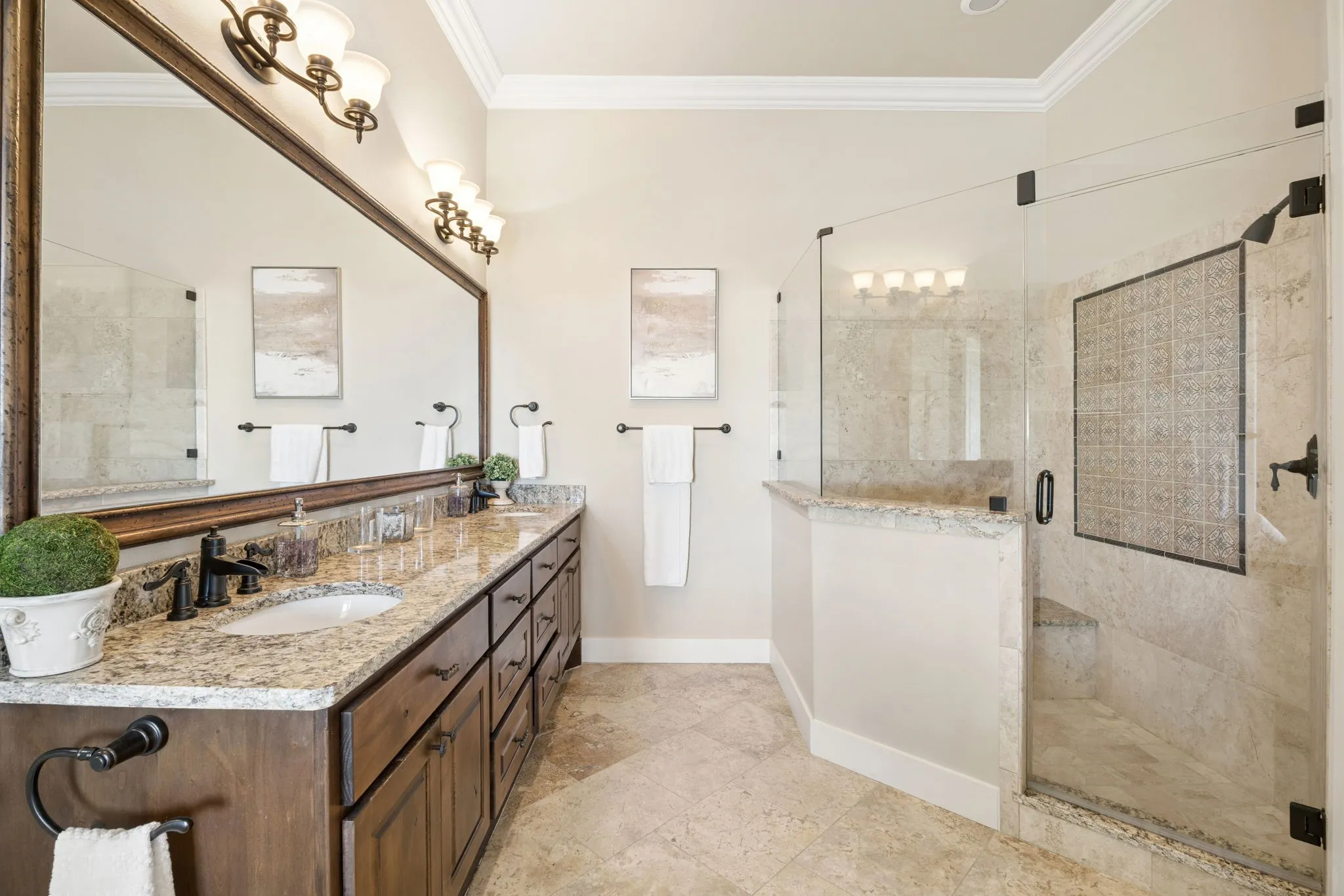 Spacious bathroom featuring a dual vanity with granite countertops, rich wood cabinetry, and oil-rubbed bronze fixtures