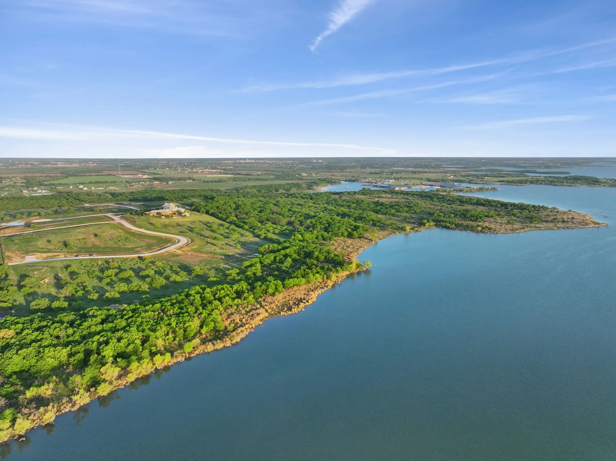 Expansive lakefront property featuring a winding shoreline, abundant green trees, and a clear blue waterway