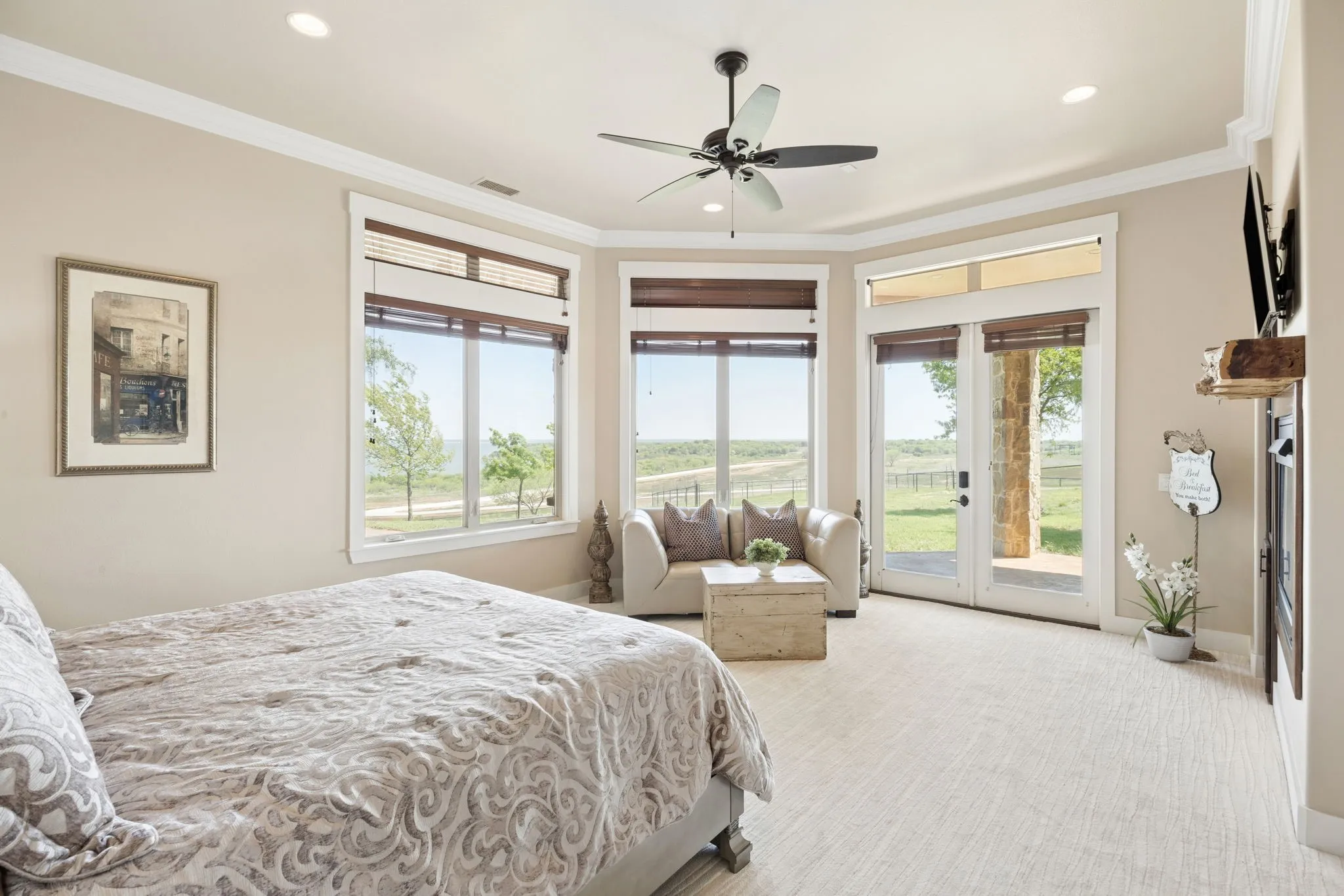 Spacious room featuring multiple windows, a ceiling fan with integrated lighting, a built-in fireplace with a wood mantle, and double glass doors providing outdoor access