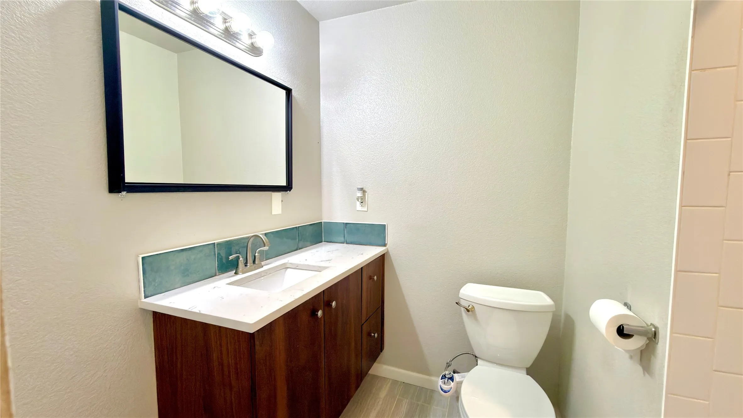 Half bath with a textured wall and vanity