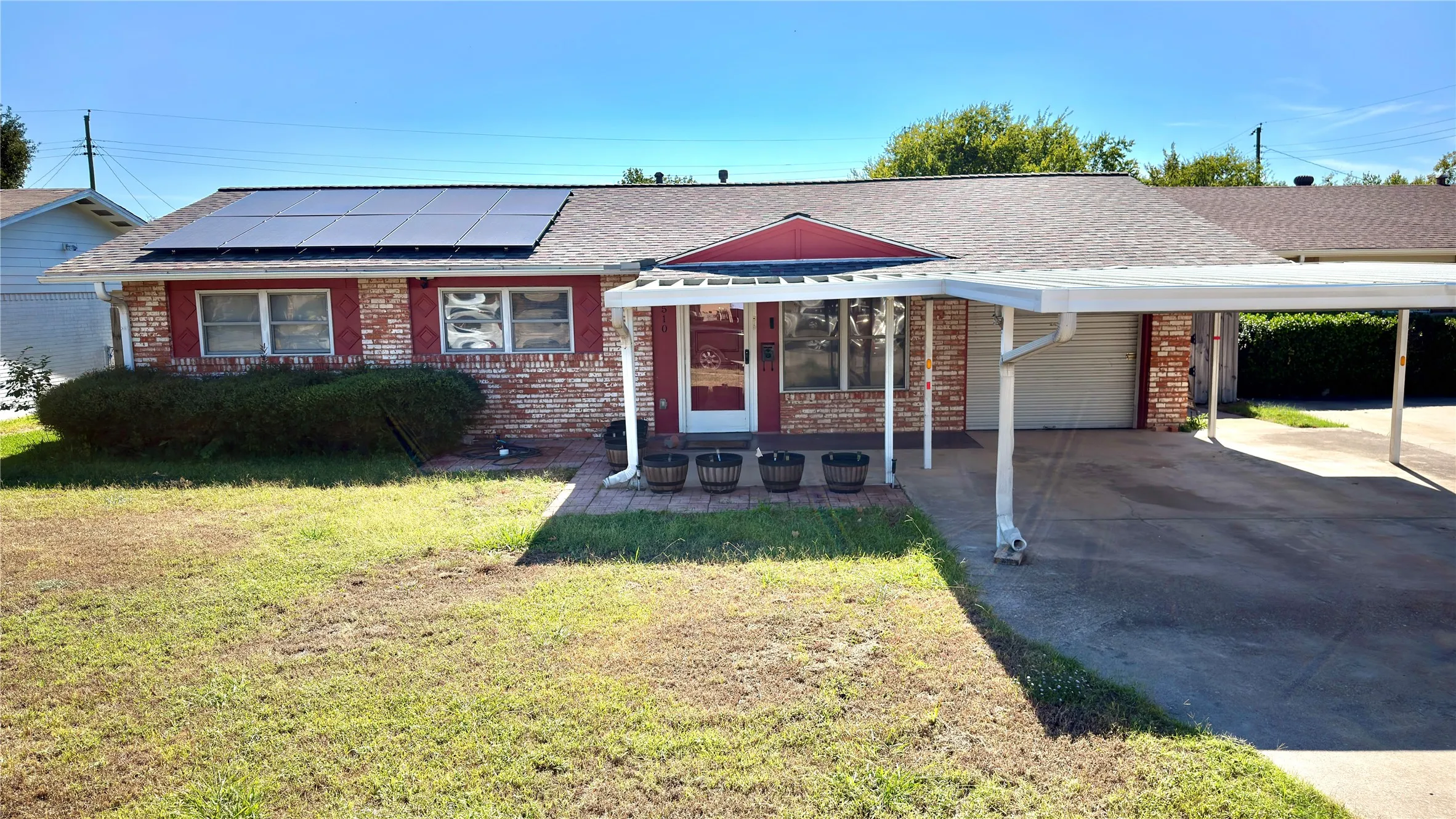 Ranch-style home with a shingled roof, a carport, brick siding, and a front lawn