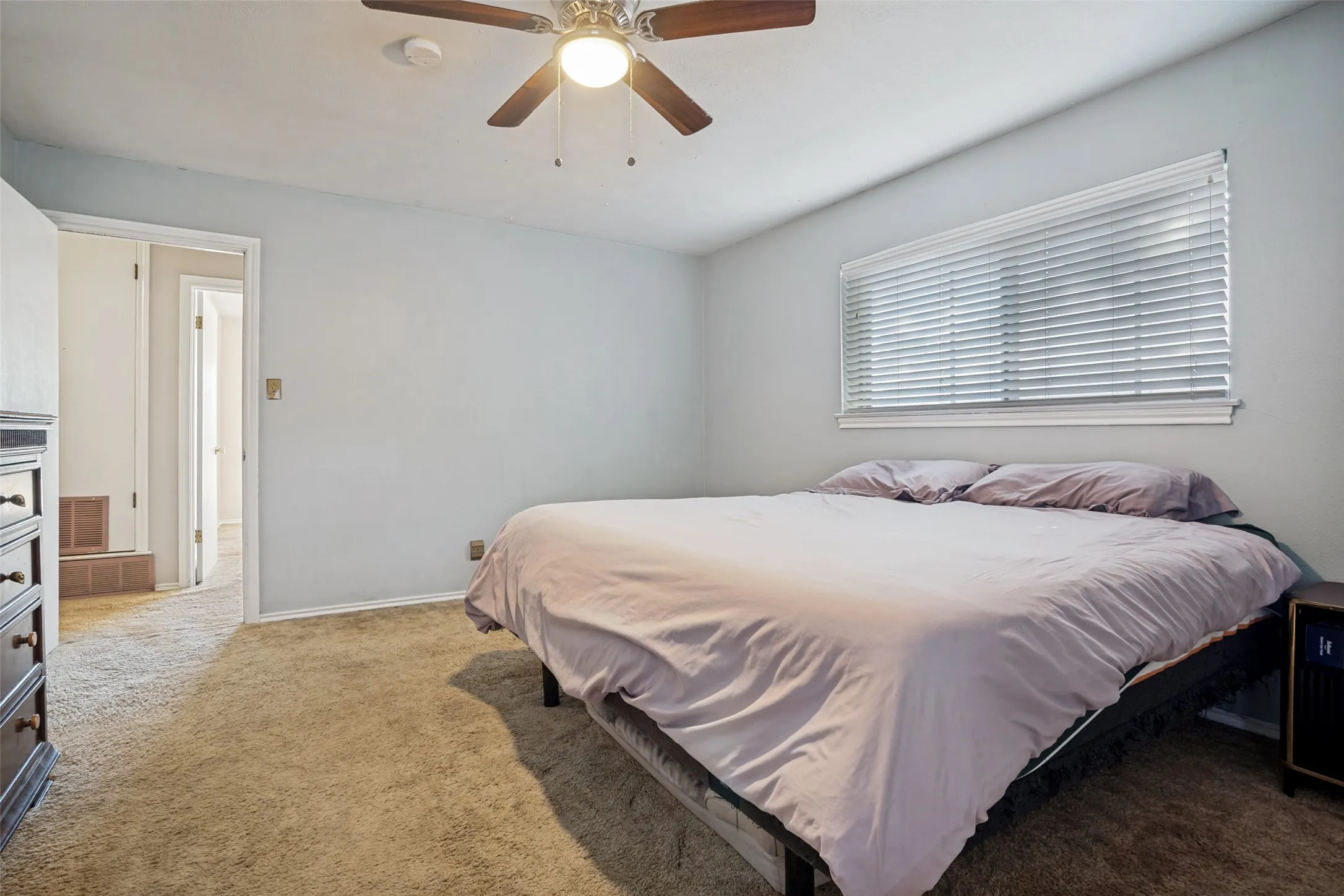 Wall-to-wall carpeting, ceiling fan with light fixture, and a window with horizontal blinds