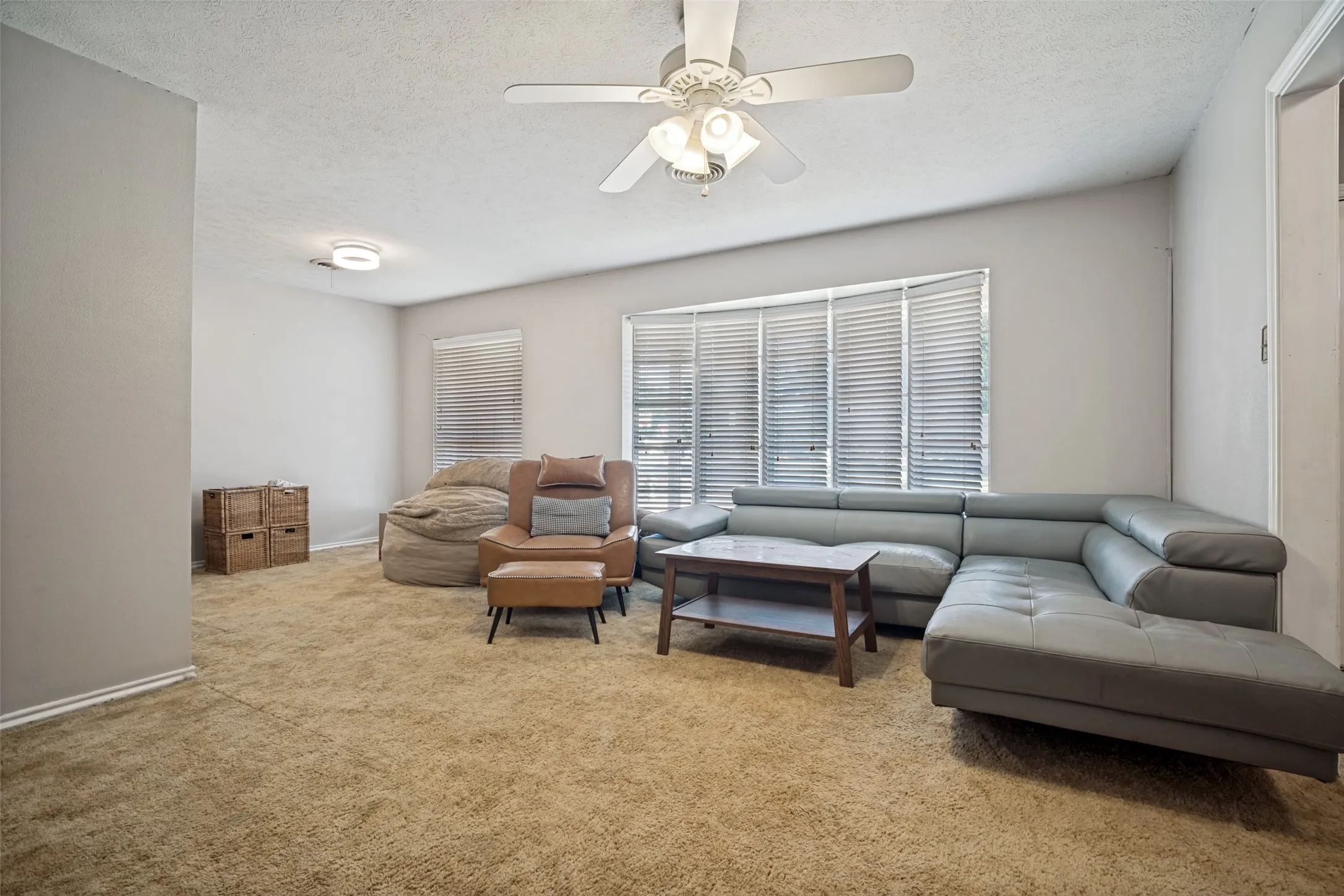Bay window with blinds, ceiling fan with integrated lighting, recessed lighting, and wall-to-wall carpeting