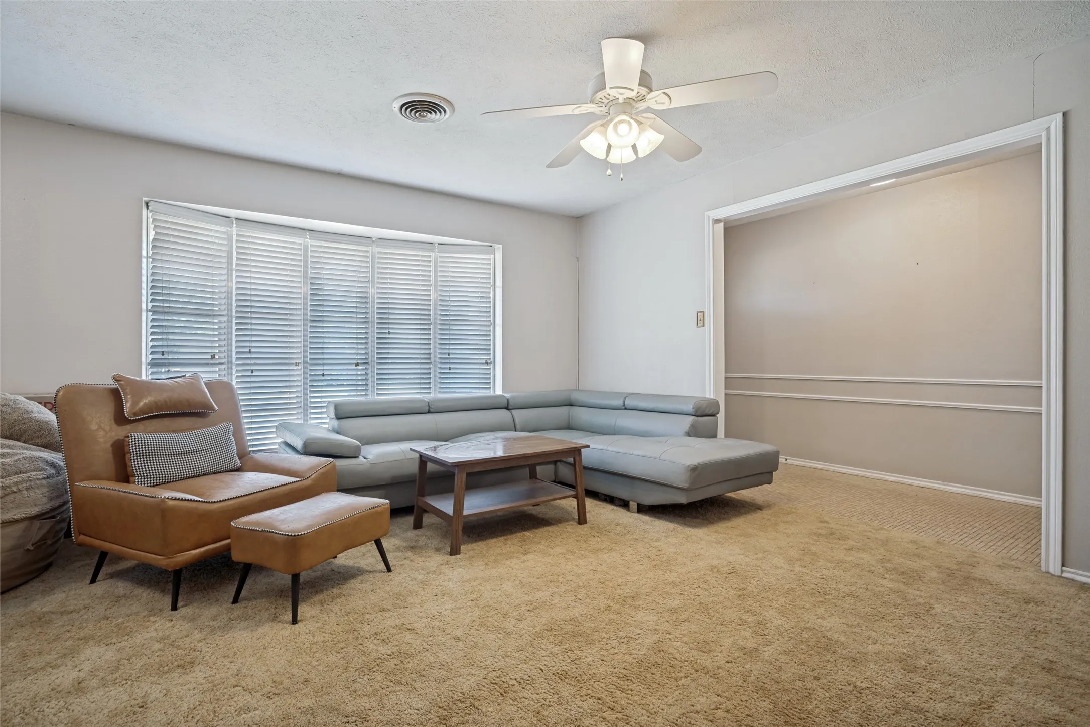 Bay window with horizontal blinds, ceiling fan with integrated lighting, wall molding, and neutral wall paint