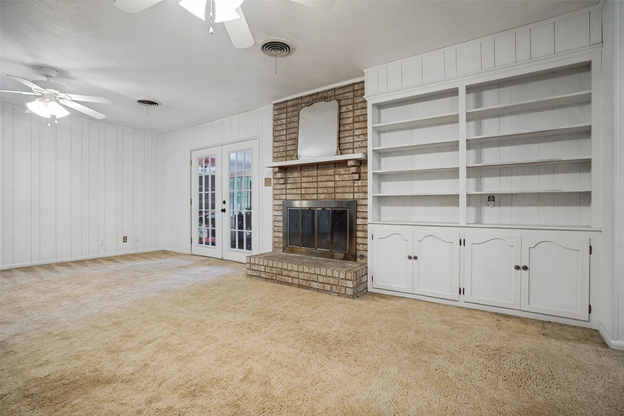 Brick fireplace with a metal firebox, flanked by extensive built-in shelving and lower cabinetry