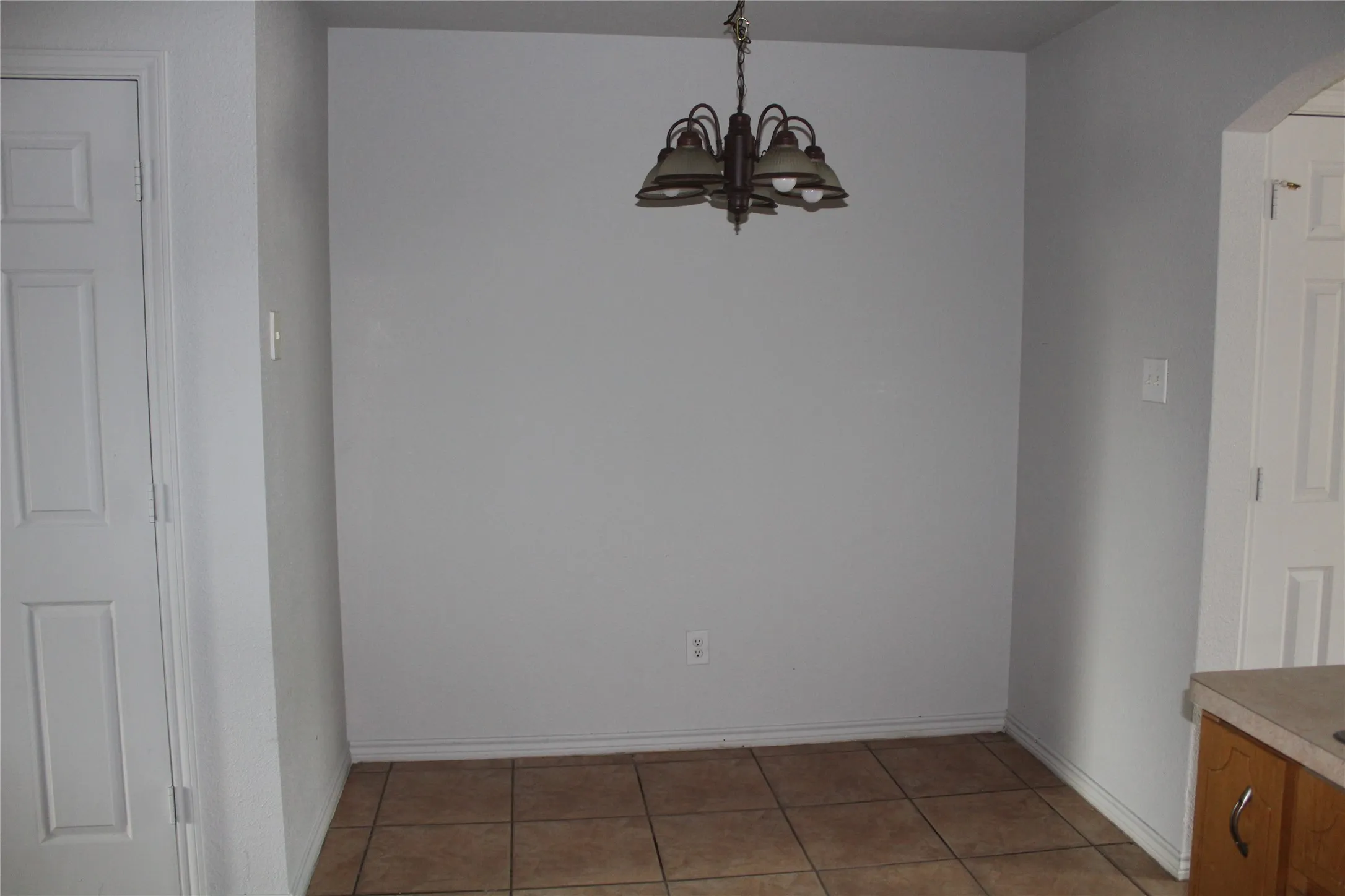 Unfurnished dining area featuring arched walkways, light tile patterned floors, and a chandelier