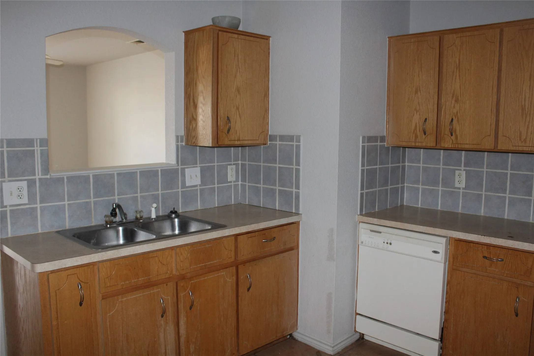 Kitchen featuring dishwasher, brown cabinets, light countertops, and backsplash
