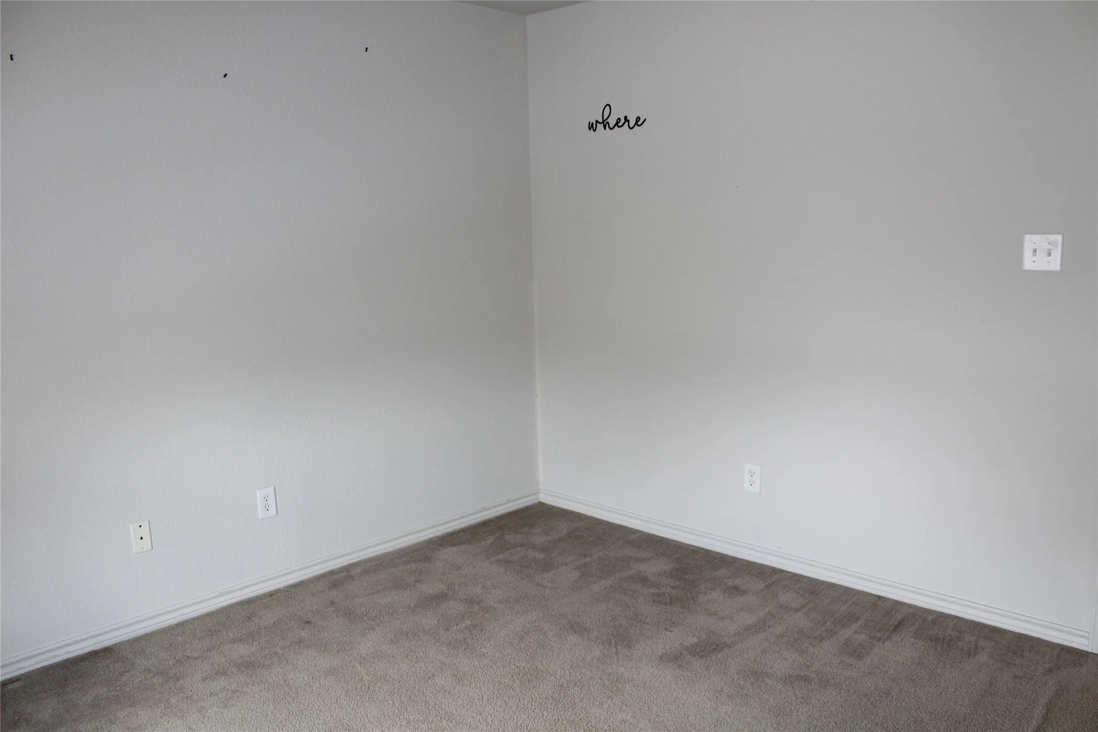 Carpeted spare room featuring baseboards