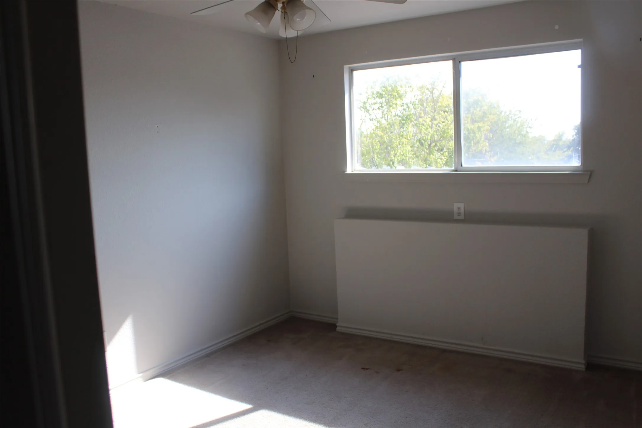 Empty room with carpet, ceiling fan, and radiator heating unit