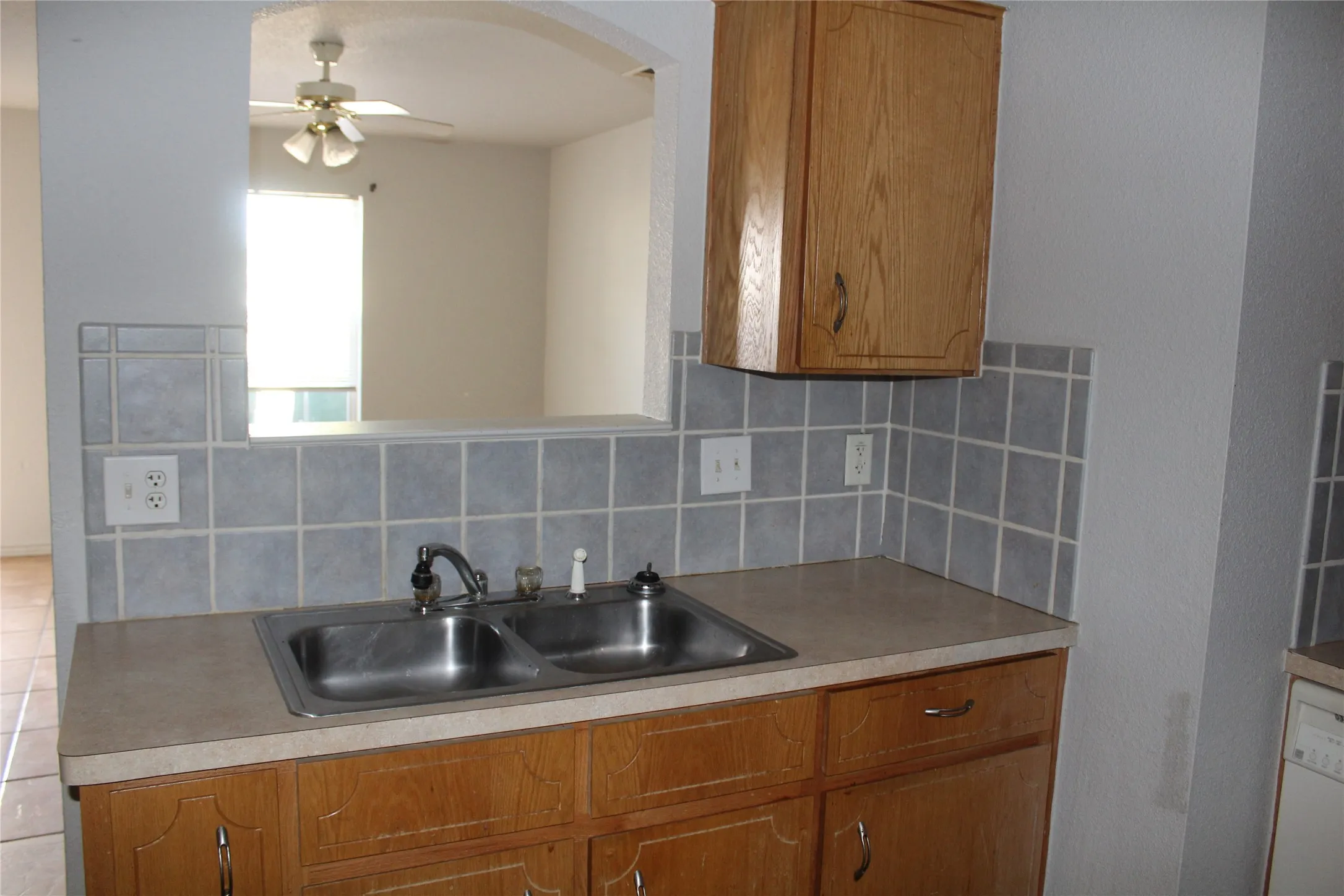 Kitchen with brown cabinets, tasteful backsplash, ceiling fan, and light countertops