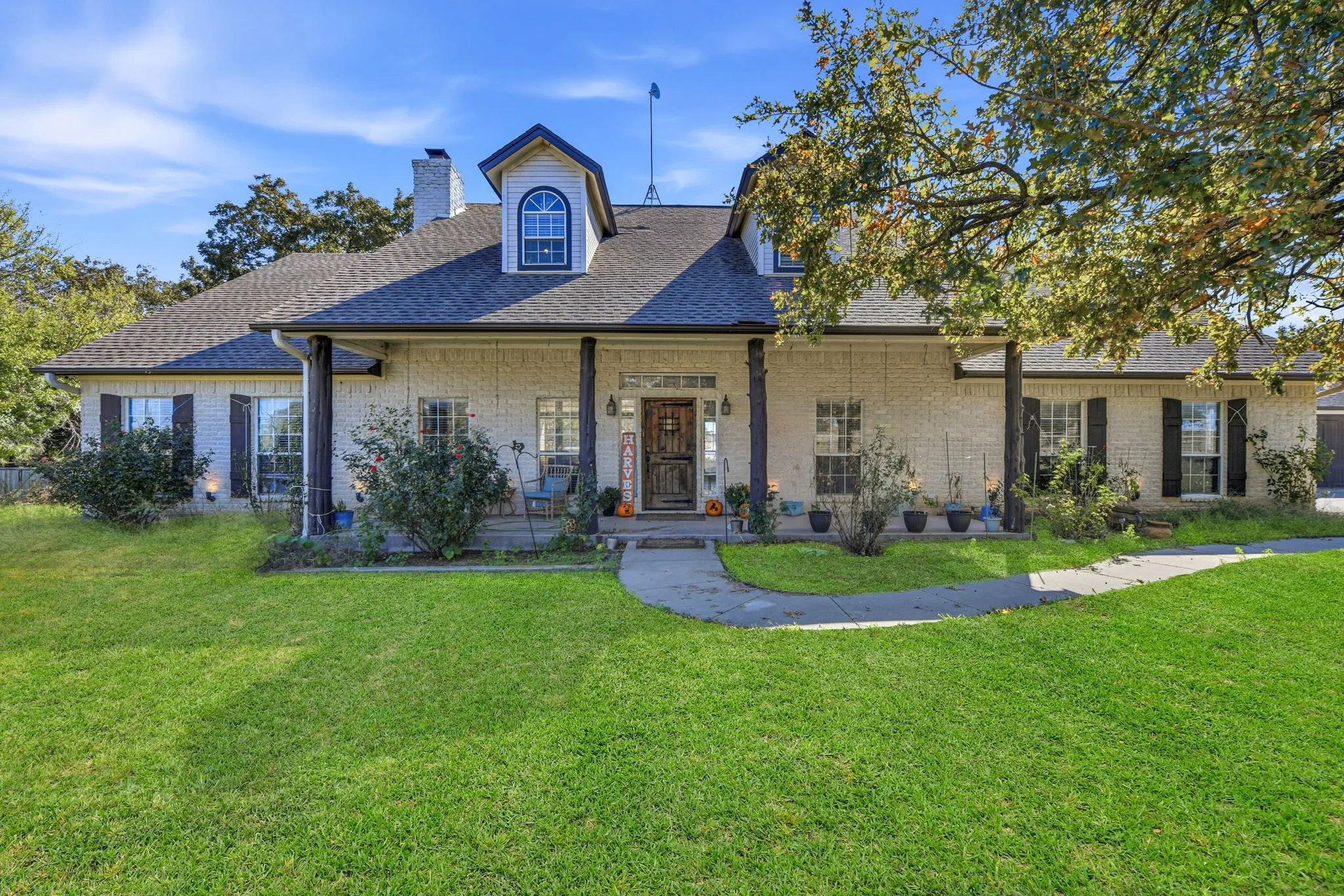 View of front of house with roof with shingles, a front lawn, a porch, and brick siding