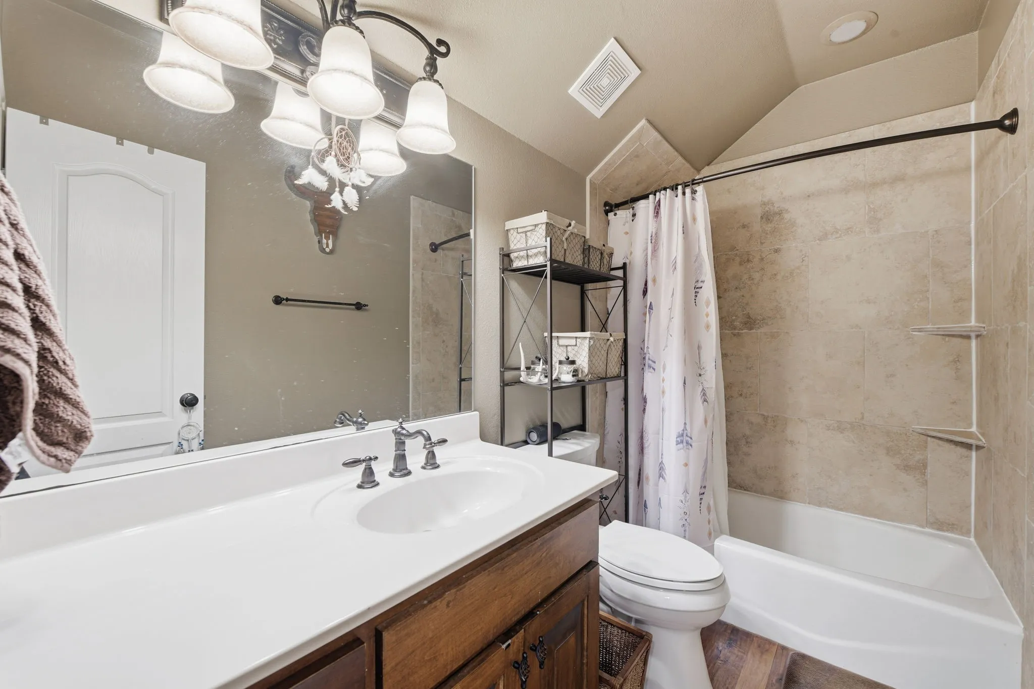 Bathroom featuring vanity, shower / tub combo with curtain, lofted ceiling, and wood finished floors