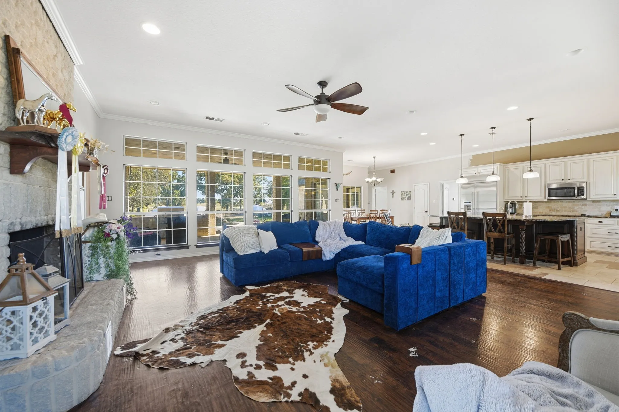 Living room featuring crown molding, a chandelier, a large fireplace, ceiling fan, and wood finished floors