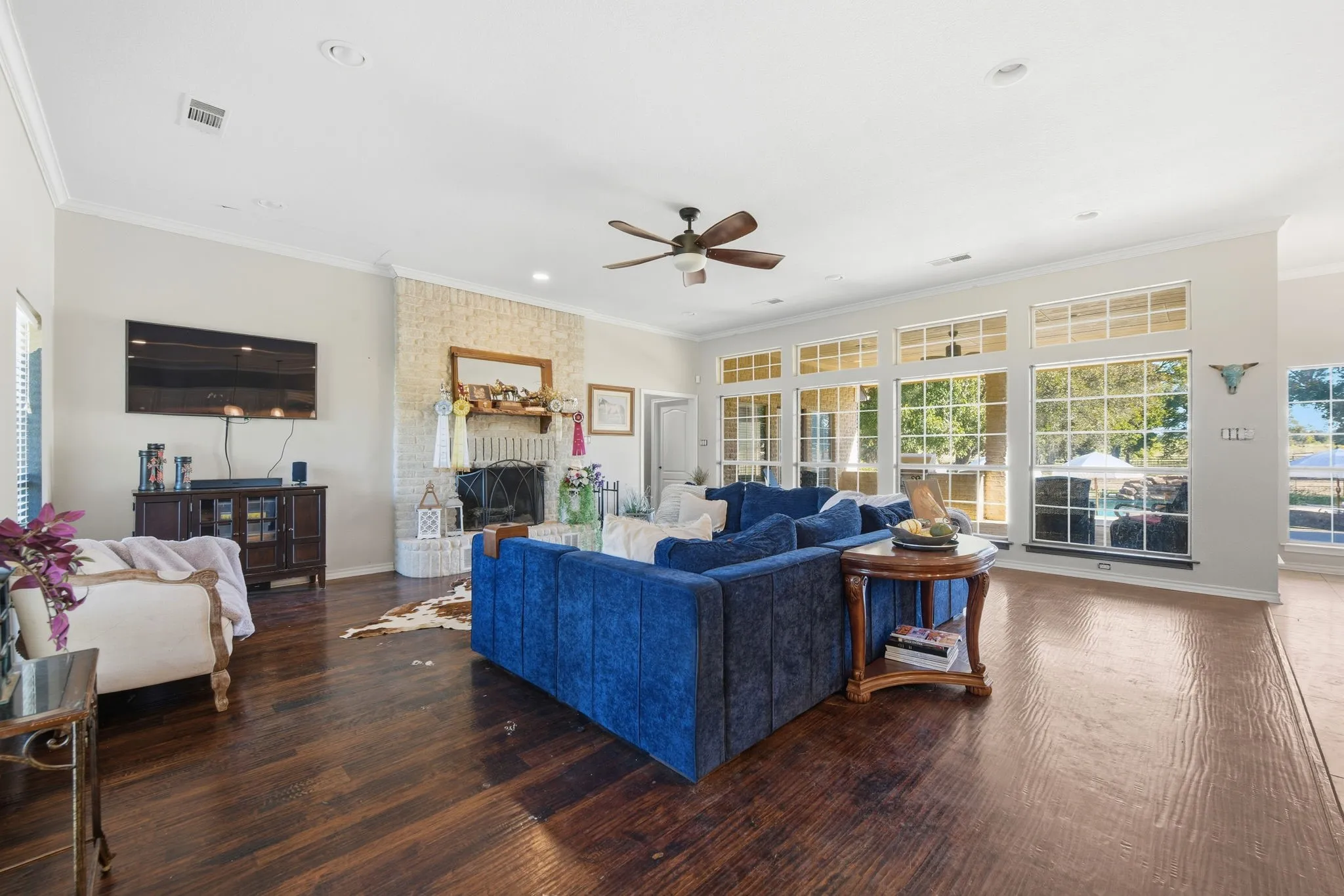 Living area with crown molding, dark wood-style floors, a large fireplace, ceiling fan, and recessed lighting