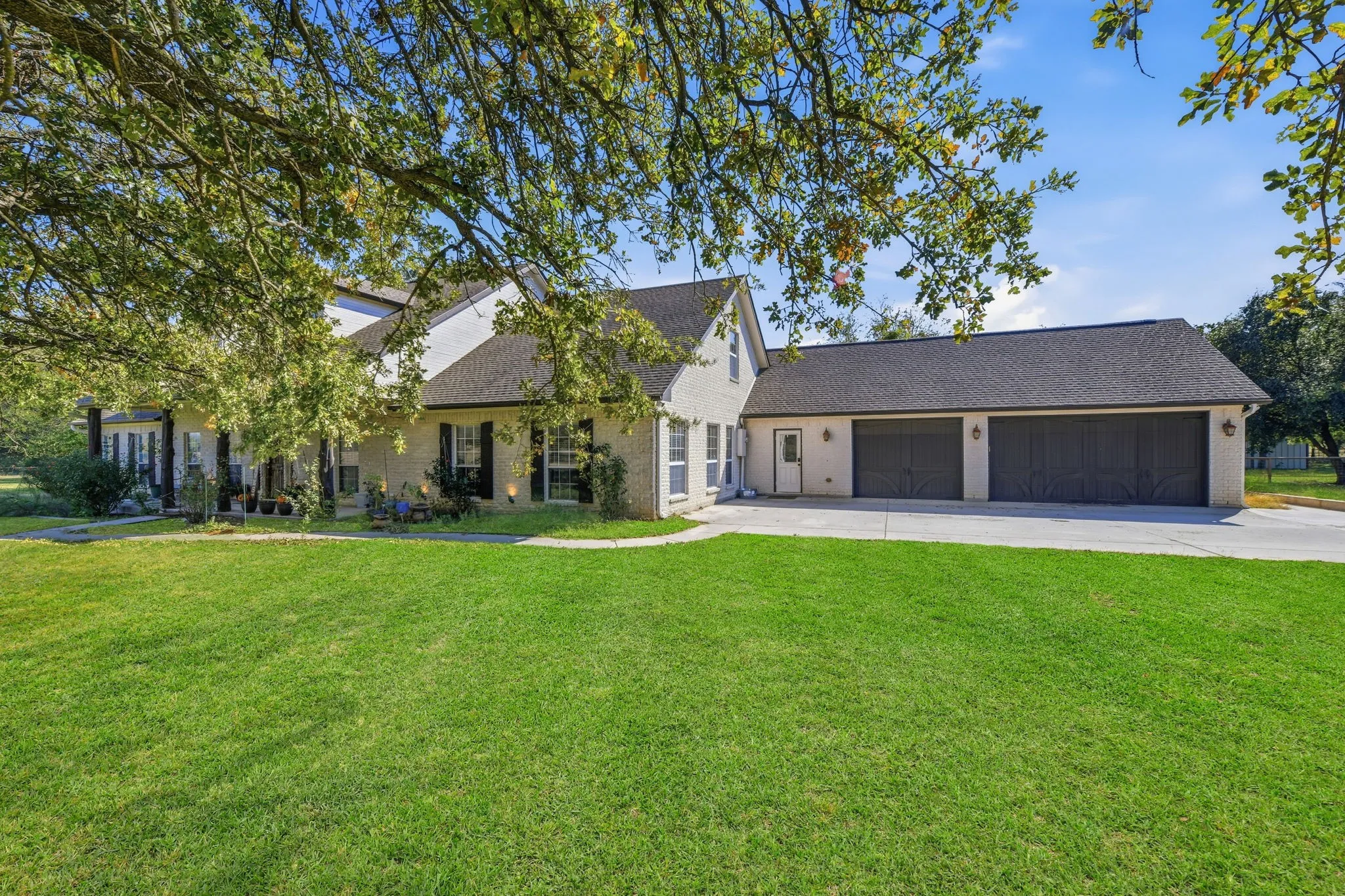 View of front of house with a shingled roof, a front lawn, brick siding, and concrete driveway