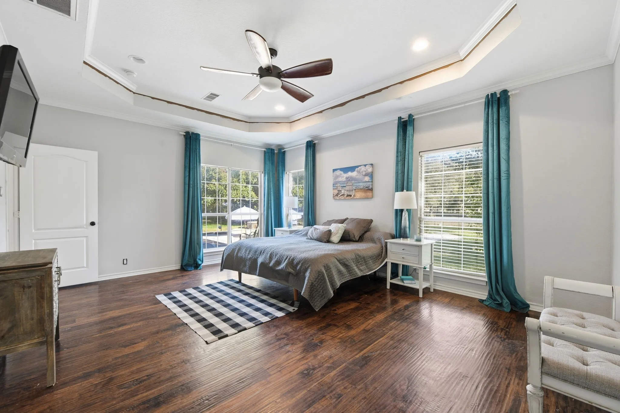 Bedroom with a tray ceiling, ornamental molding, dark wood-type flooring, ceiling fan, and recessed lighting